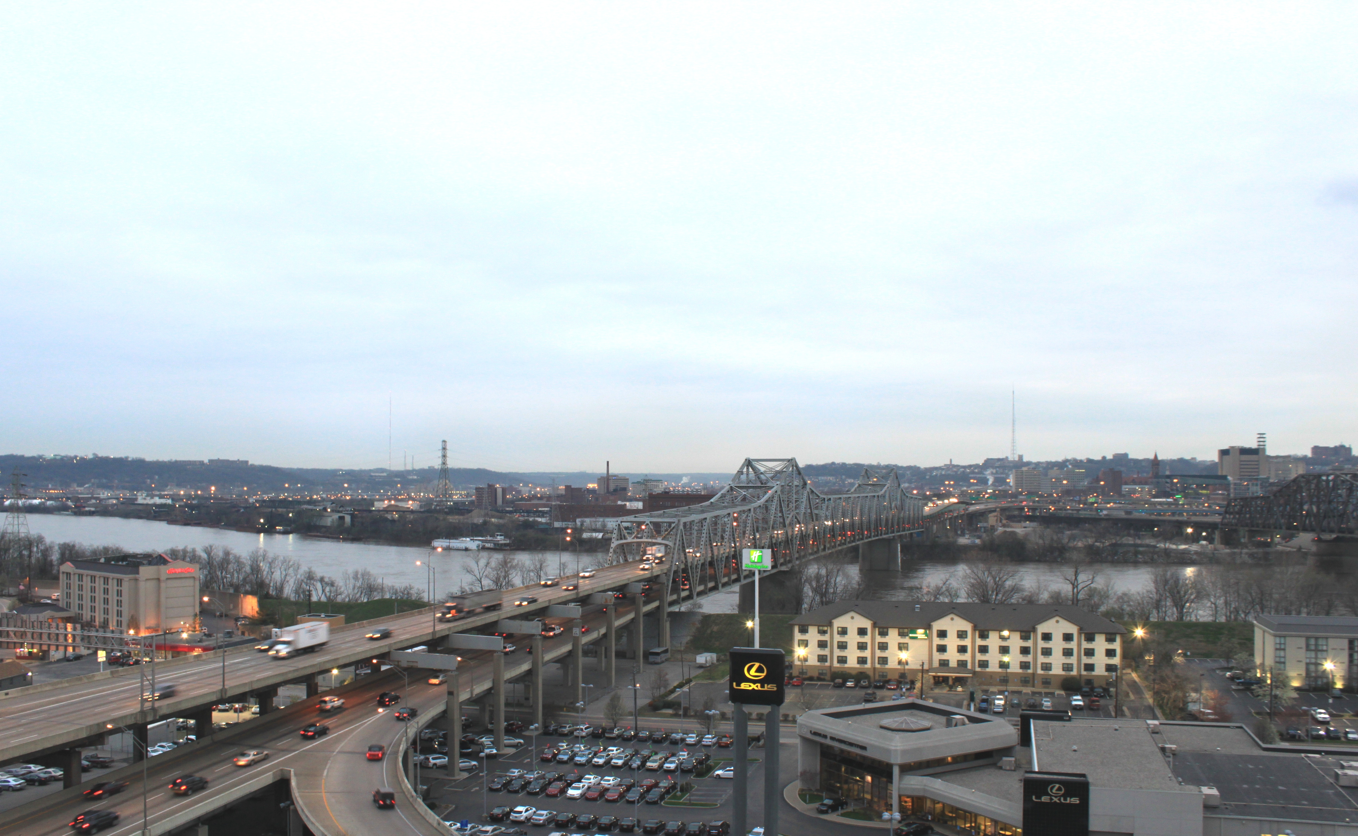 Elevated view of a steel truss highway bridge over a wide river with heavy traffic.