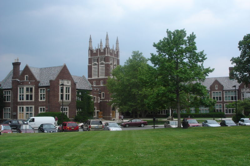 Gothic-style red brick school building with a central tower and green lawn.