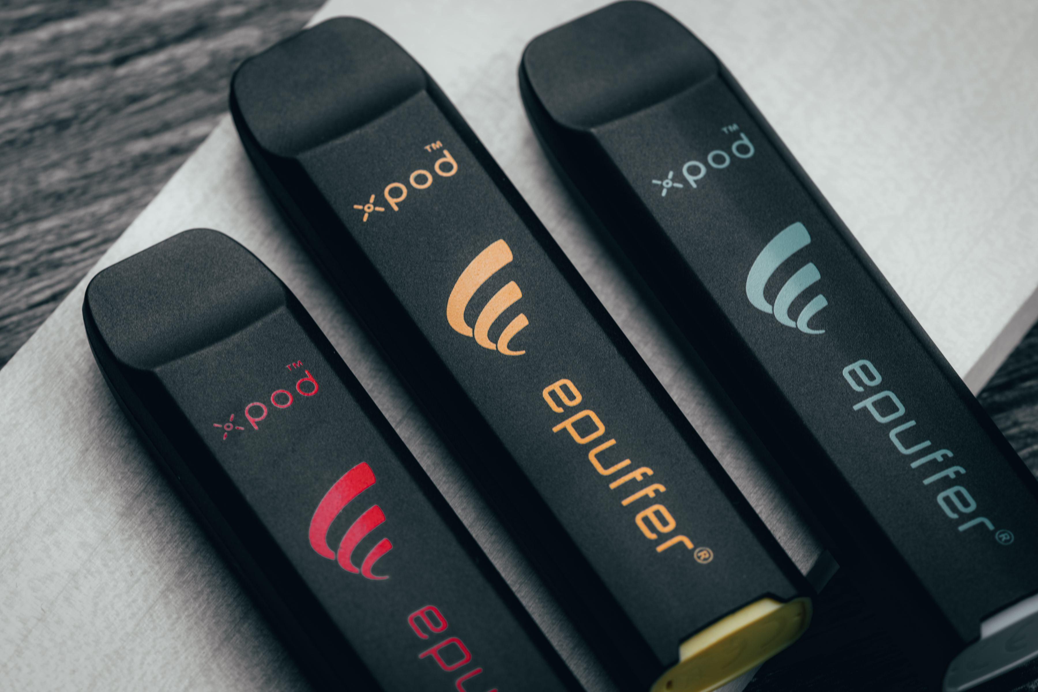 Three black disposable e-cigarette pens lined up side by side.