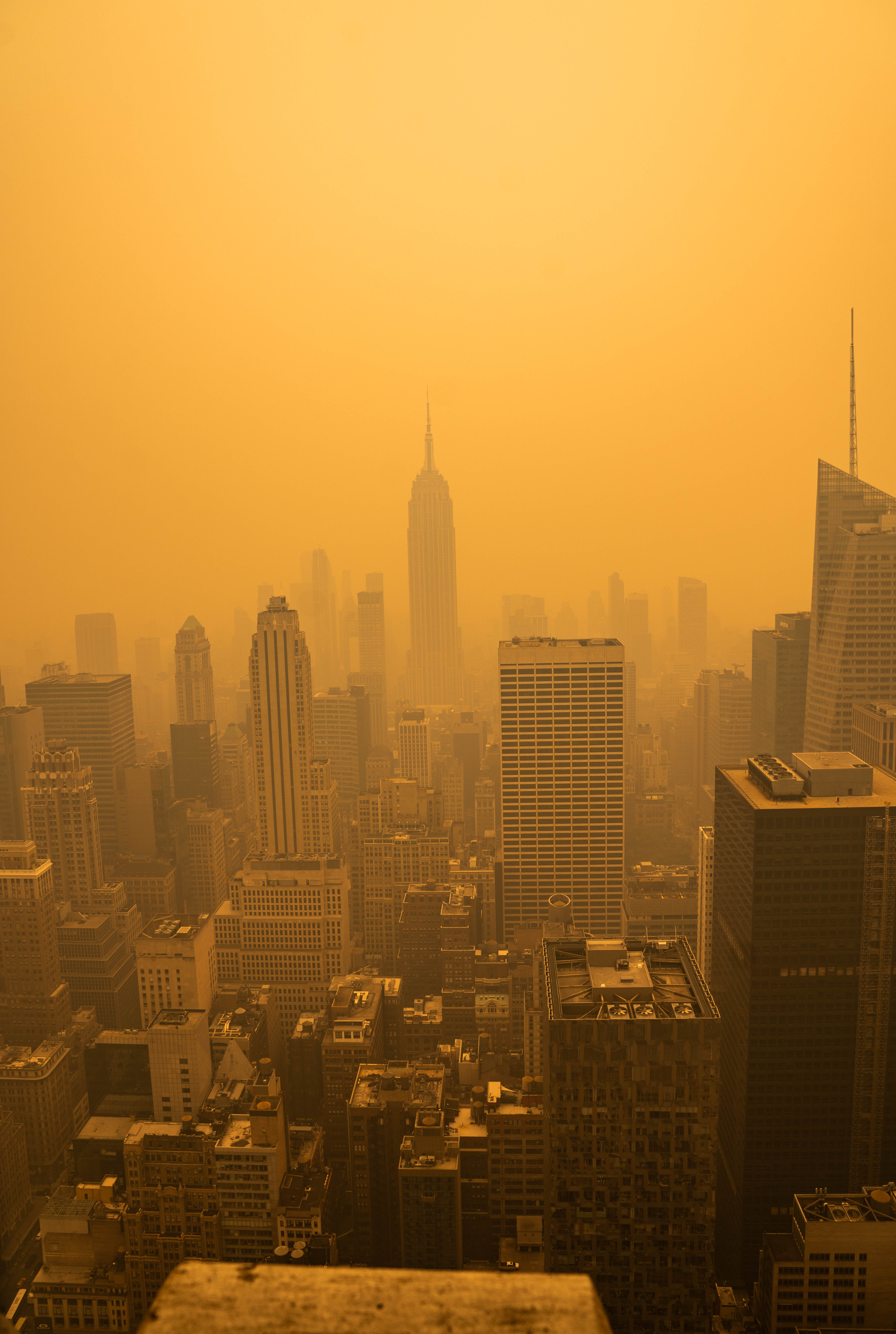 City skyline barely visible through dense orange-yellow wildfire smoke haze.