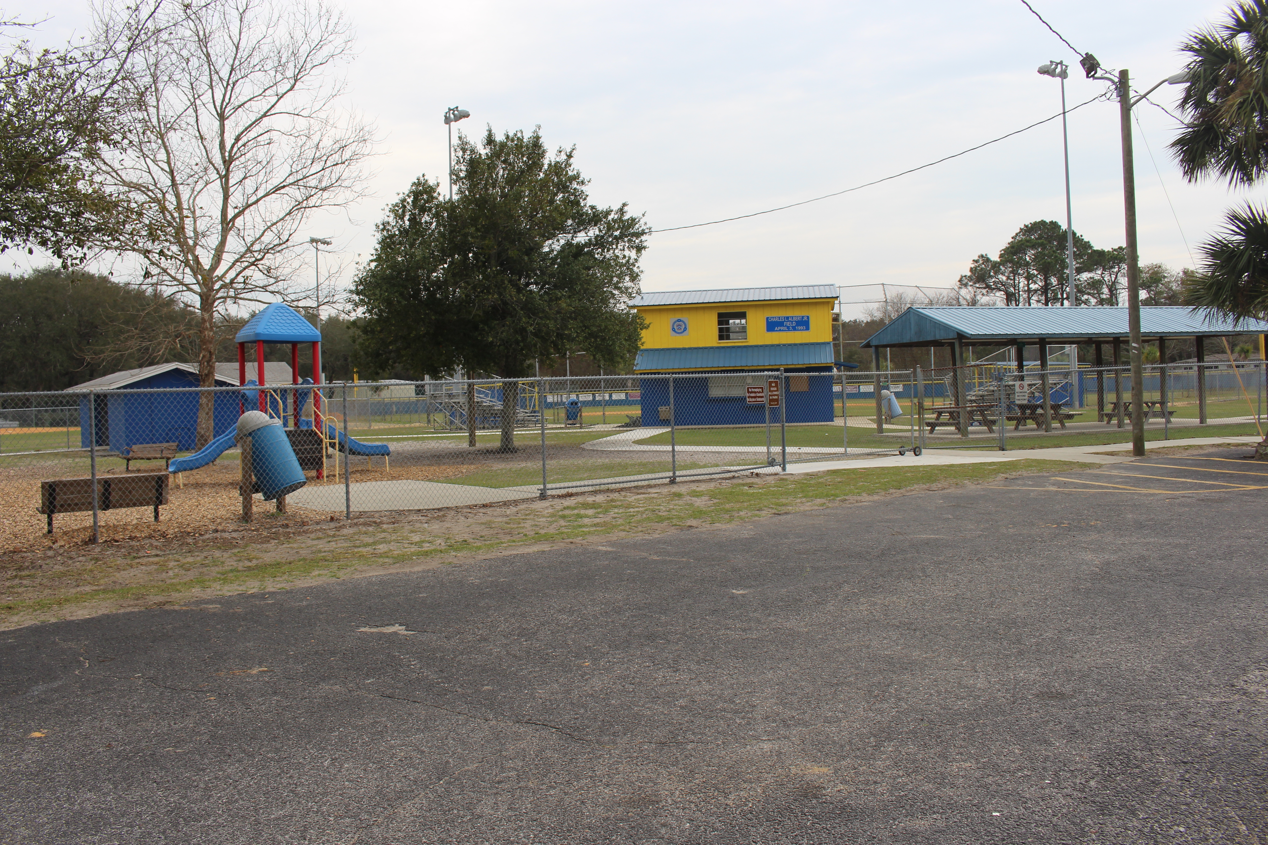 Blue and yellow recreation center building with playground and covered pavilion.