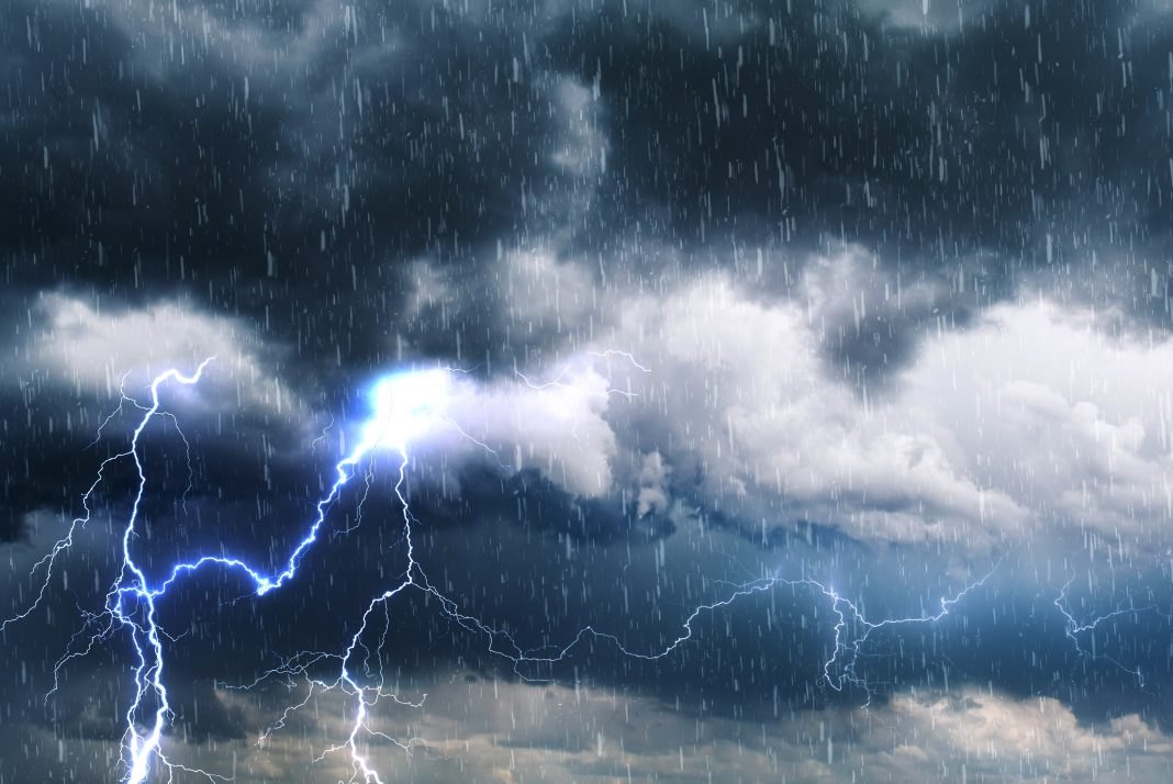 Bright lightning bolts strike during a heavy rainstorm under dark storm clouds.