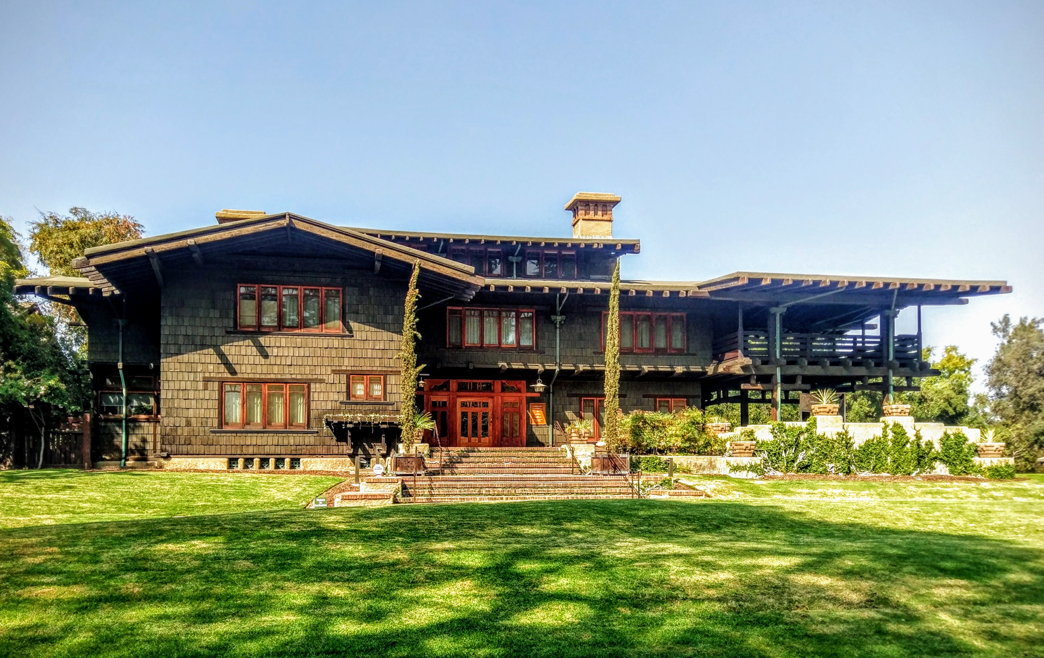 Front exterior of a two-story Craftsman-style house with dark wood shingles and a green lawn.