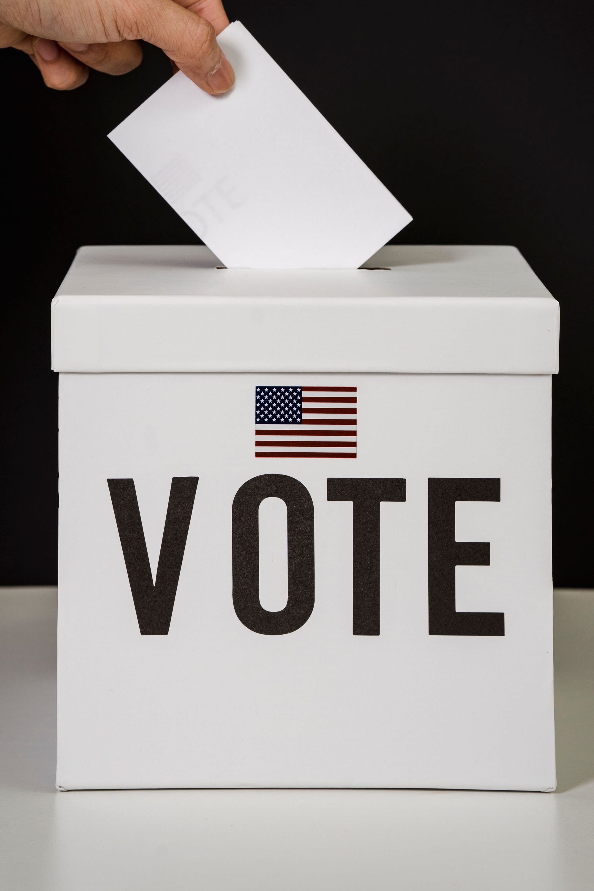 A person placing a ballot into a voting box, symbolizing democratic participation and civic duty.