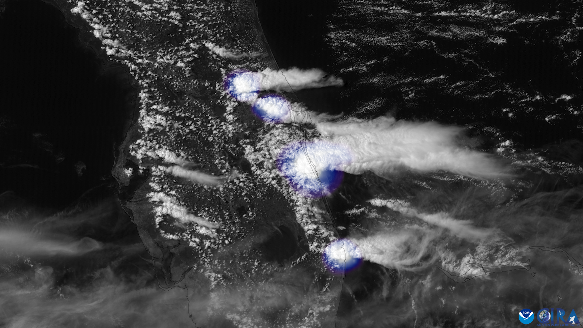 Satellite view of storm clouds with bright lightning flashes over a coastal area.
