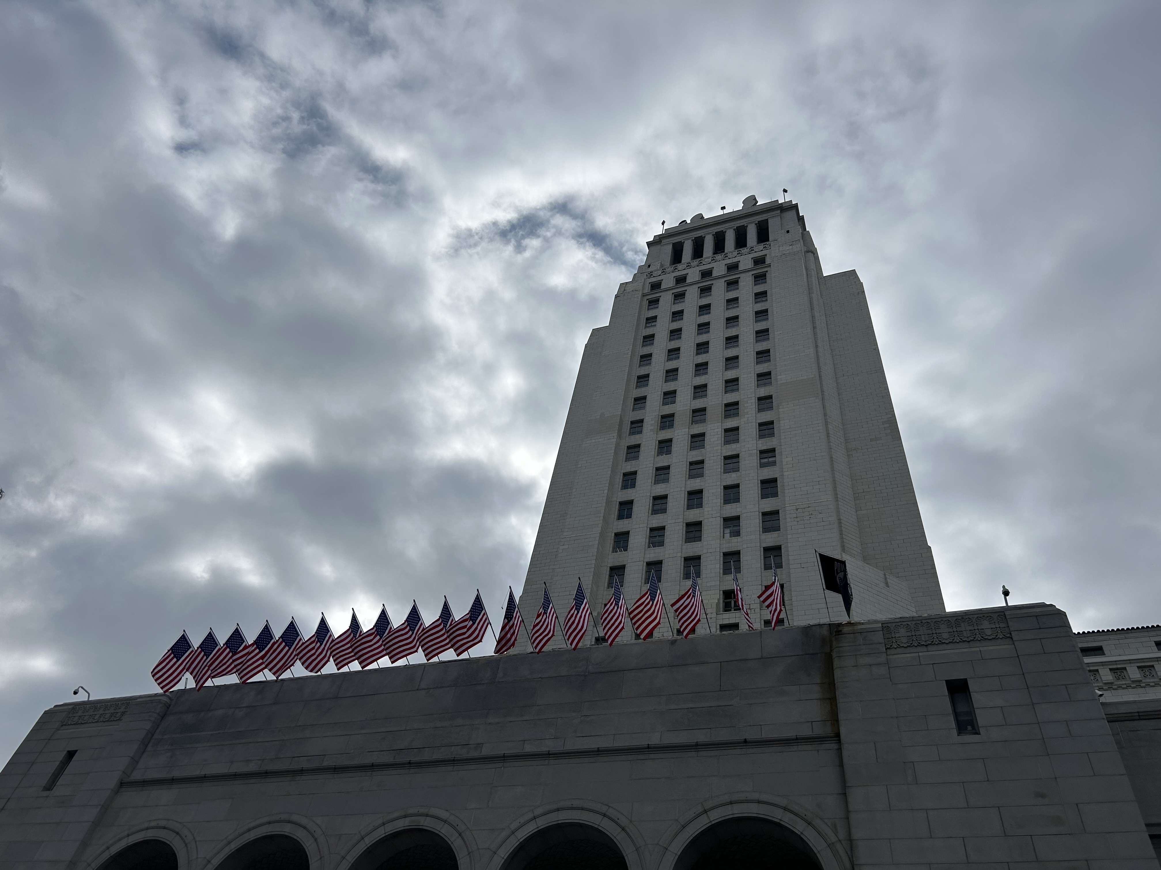 Los Angeles City Hall tower shot from below, with American flags lining the lower terrace.