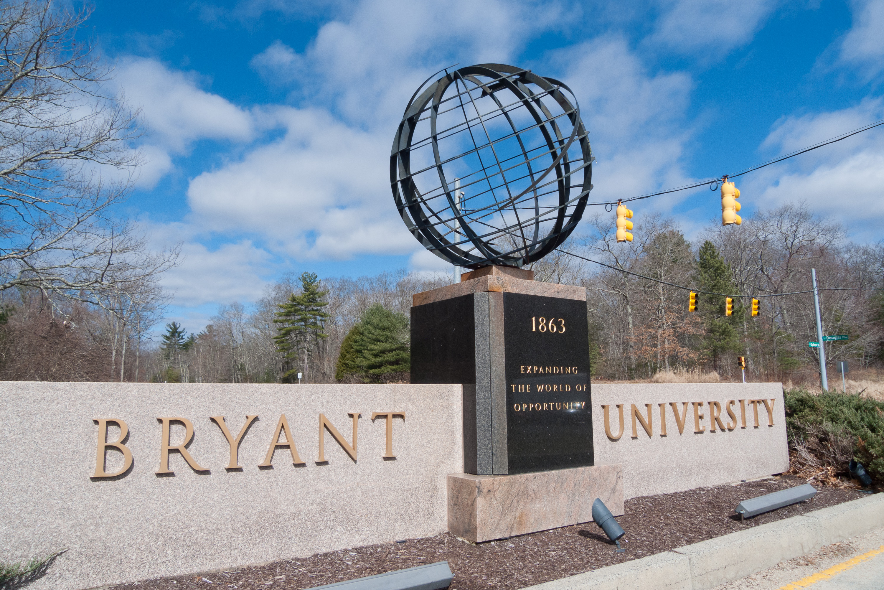 Stone entrance monument for Bryant University with a globe sculpture on top.