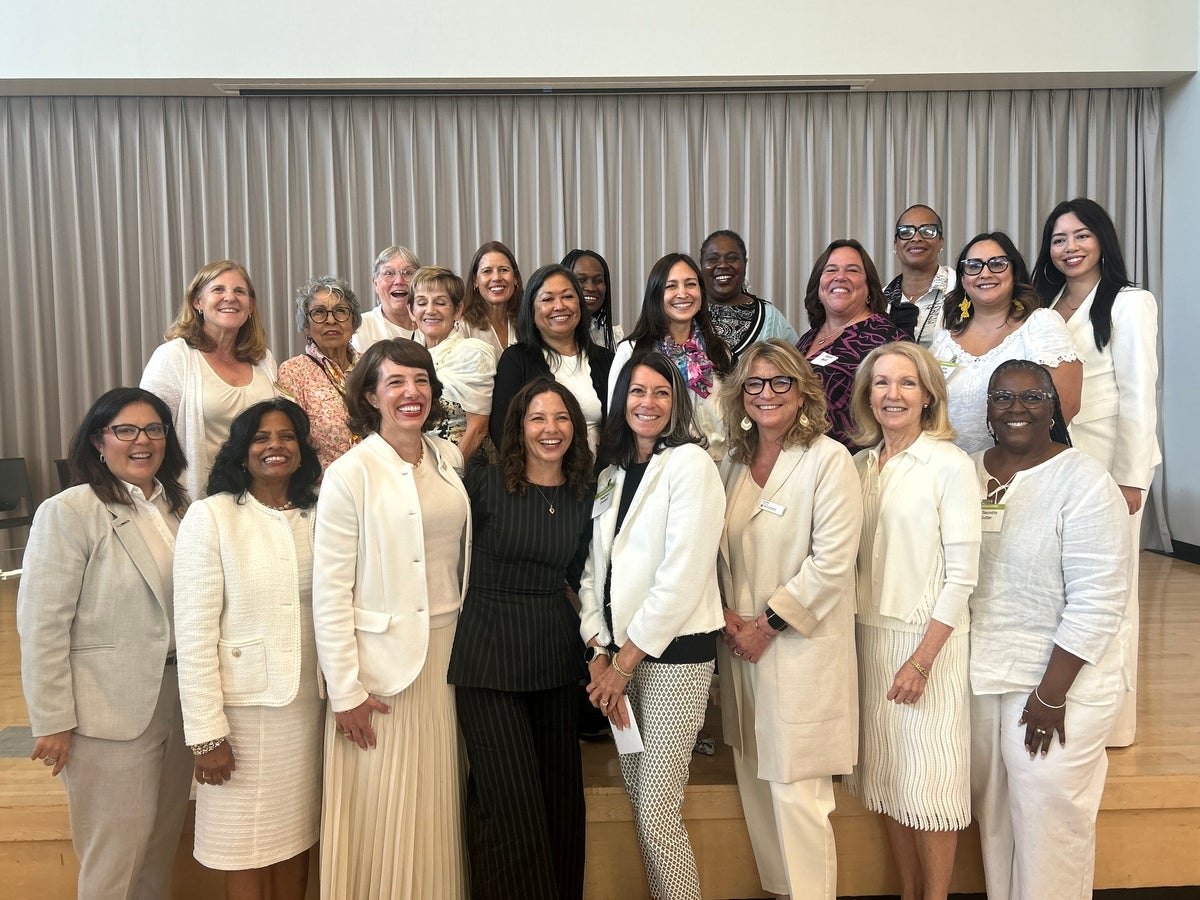 Group of about 22 women posing together indoors at a community event.