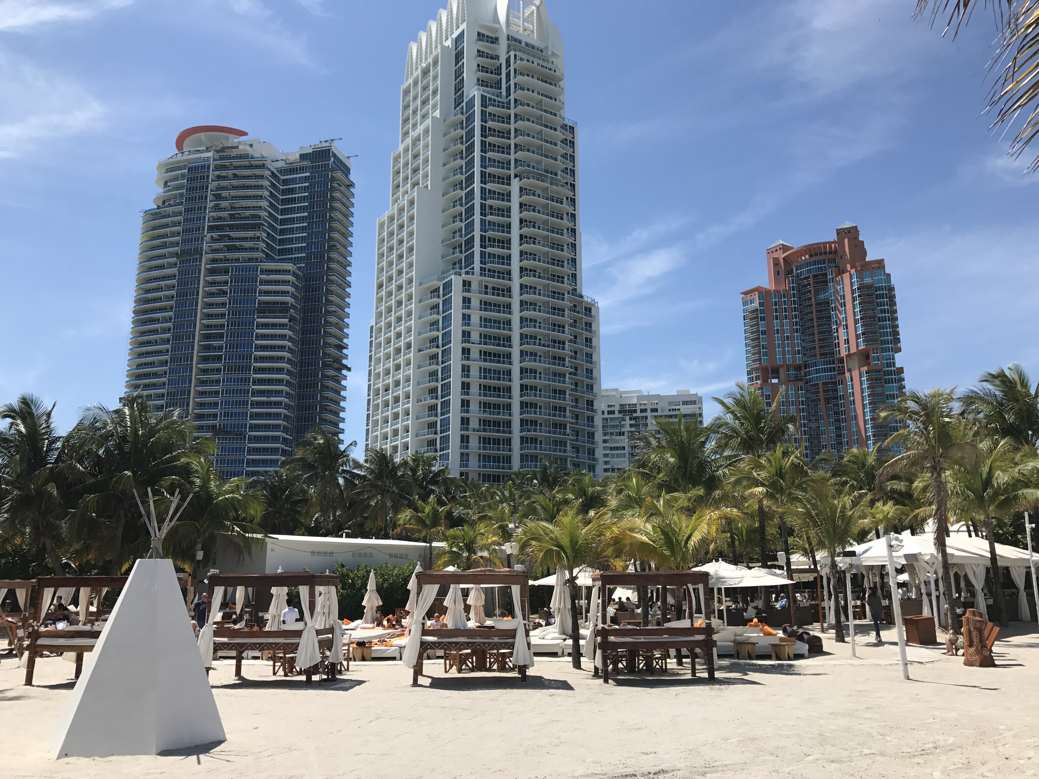 Beachfront area in South of Fifth, Miami Beach, with cabanas, palm trees, and luxury towers.
