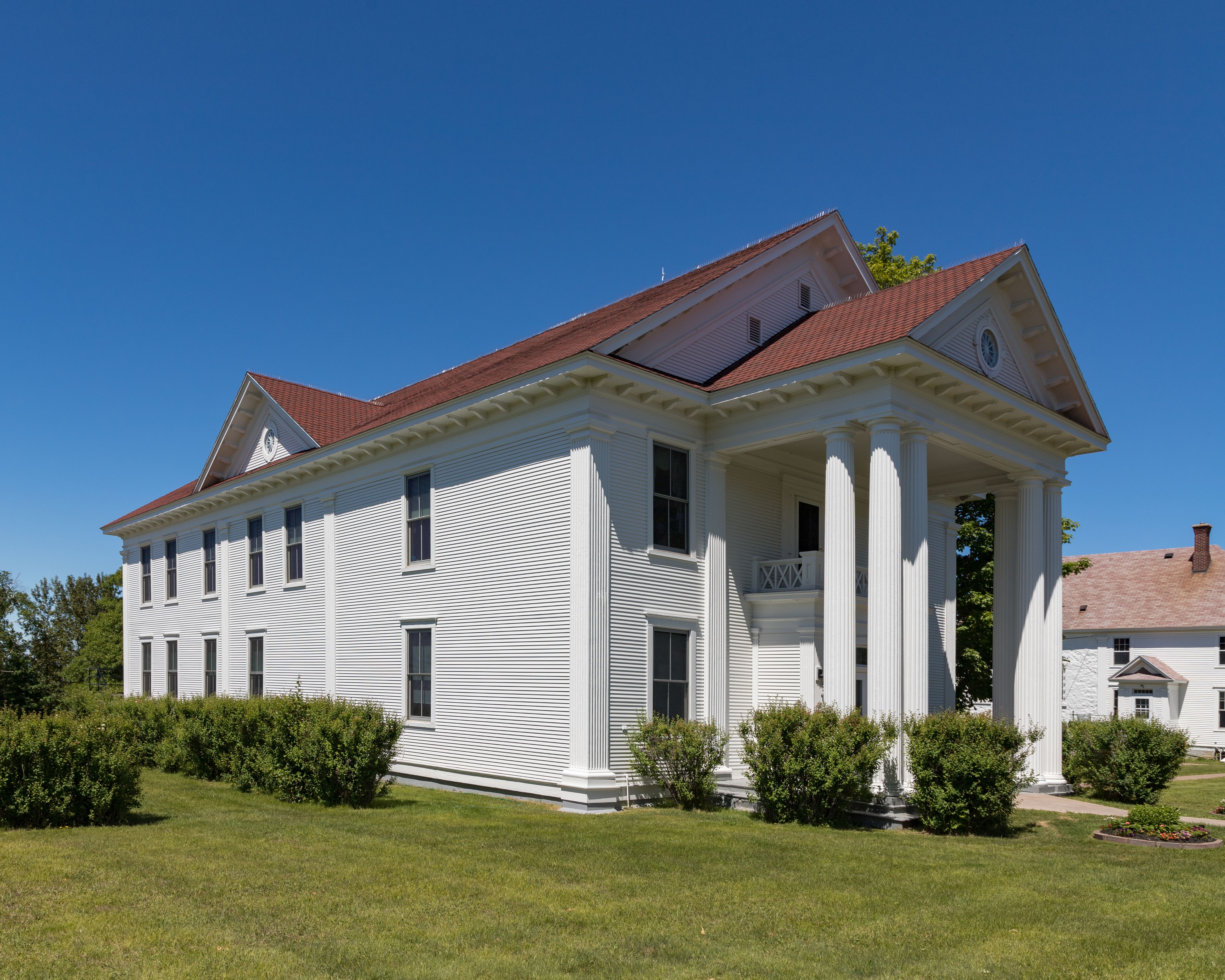 White neoclassical courthouse with large Doric columns and red roof.