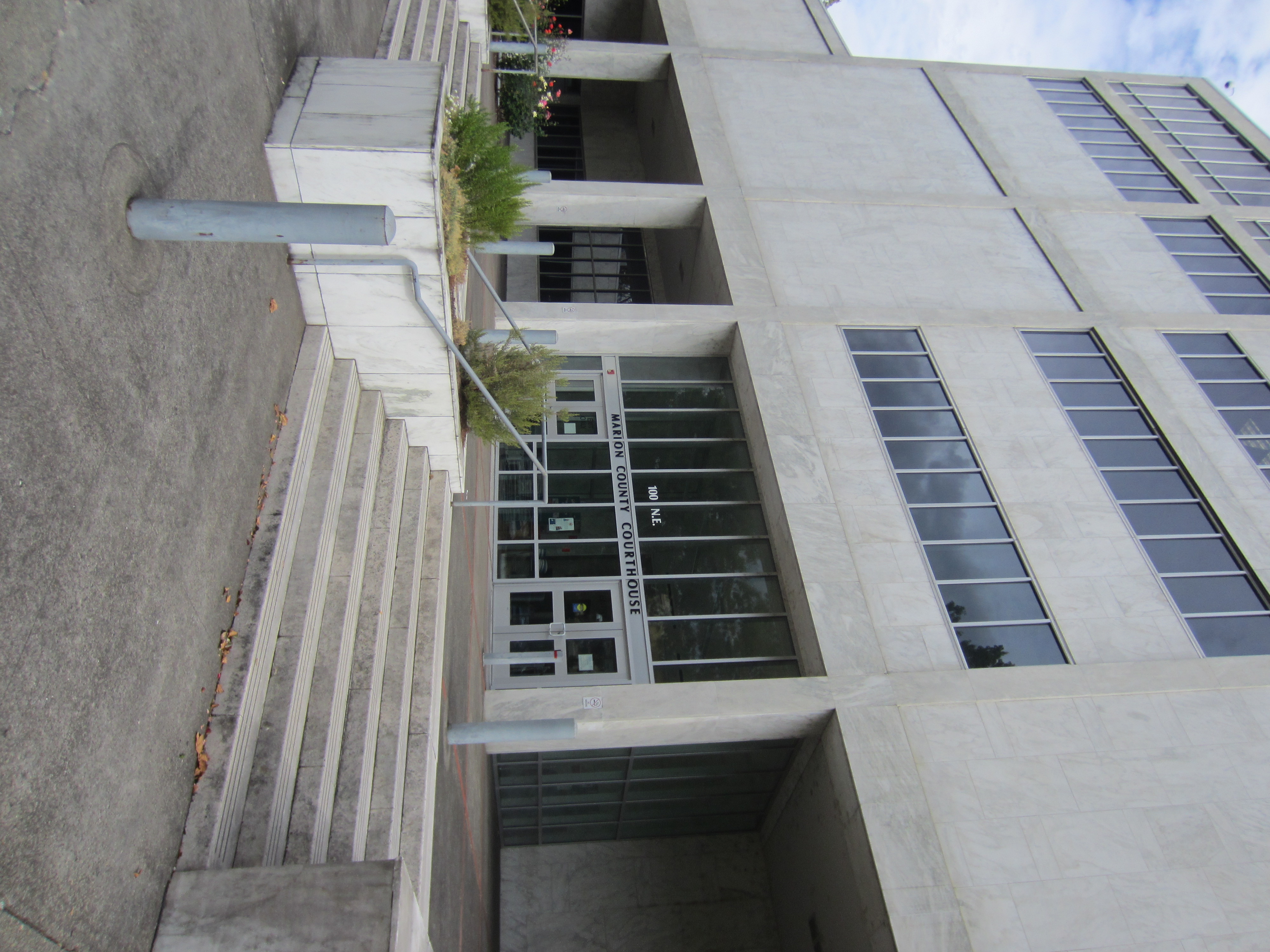 Entrance of a multi-story concrete government building with steps and glass doors.
