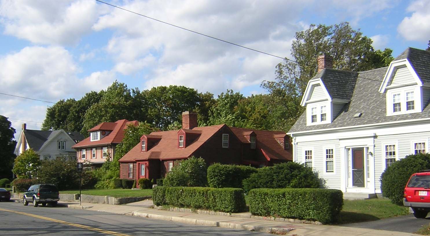 Row of historic New England-style homes along a quiet, tree-lined street.