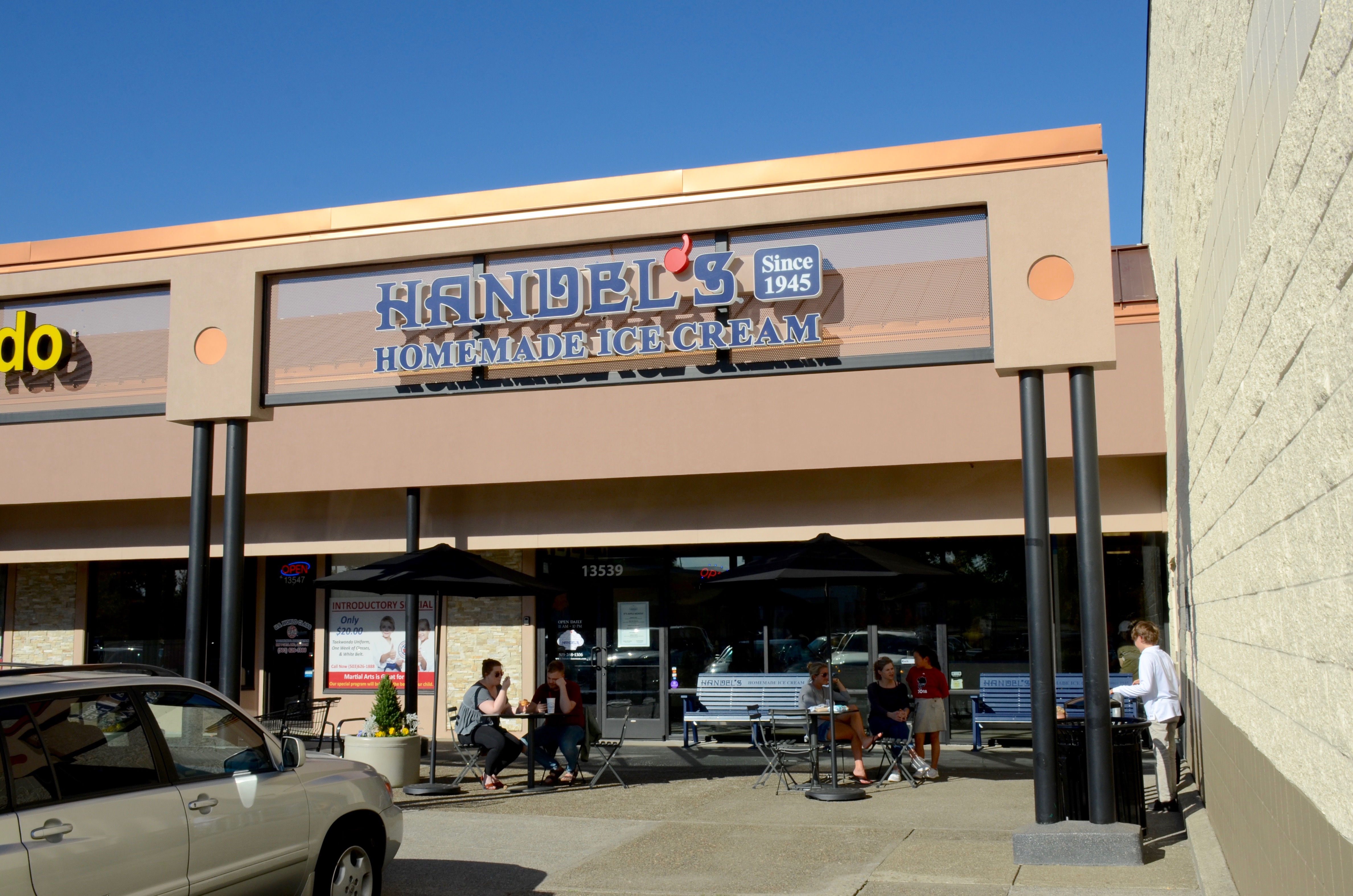 Exterior of a Handel's ice cream shop with outdoor umbrella tables and a branded sign.