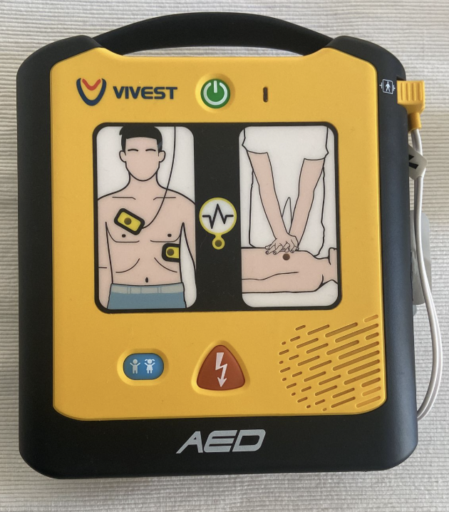 Yellow and black AED device with electrode pad placement diagrams on front.