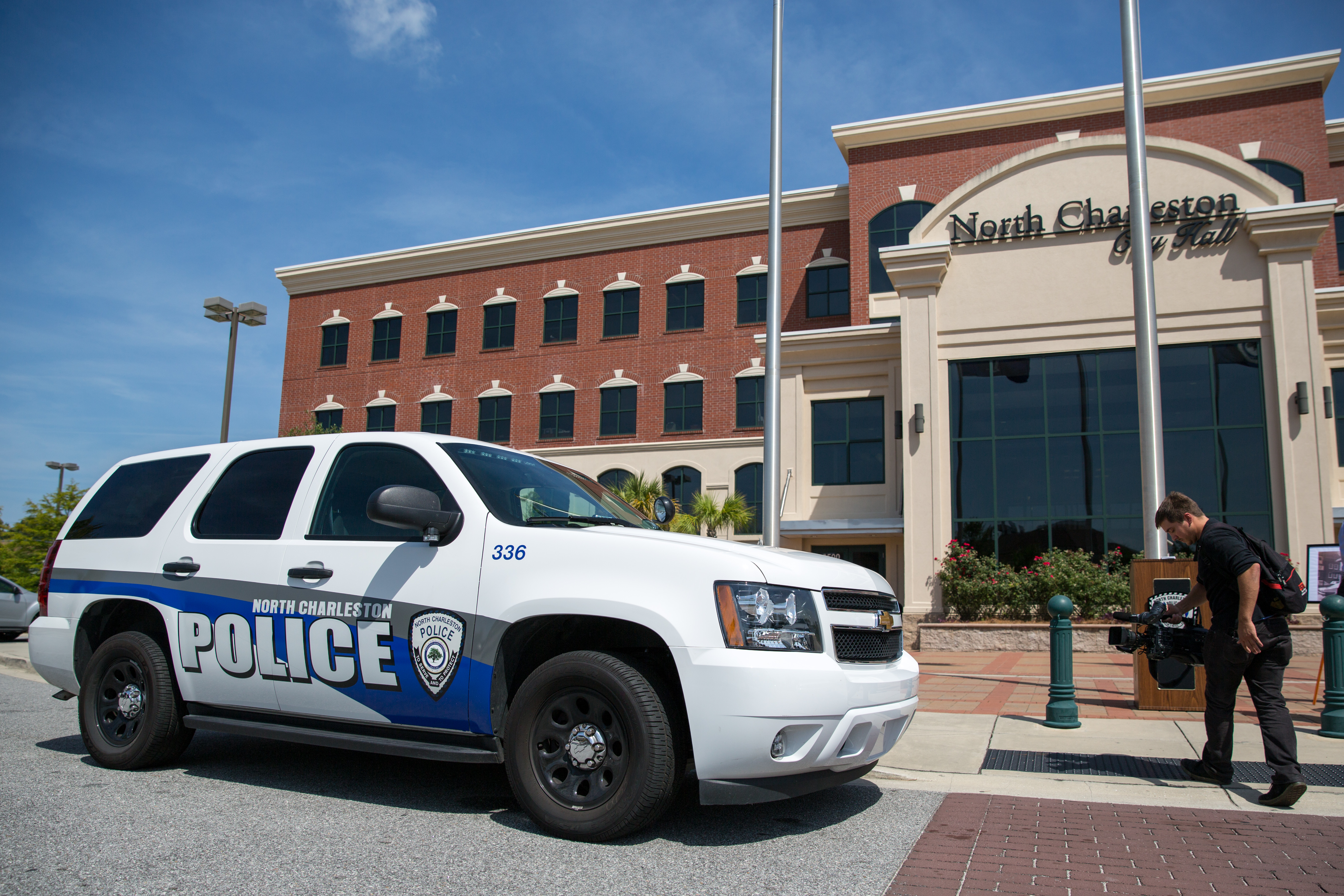 A marked North Charleston Police Department SUV parked outside a brick city hall building.