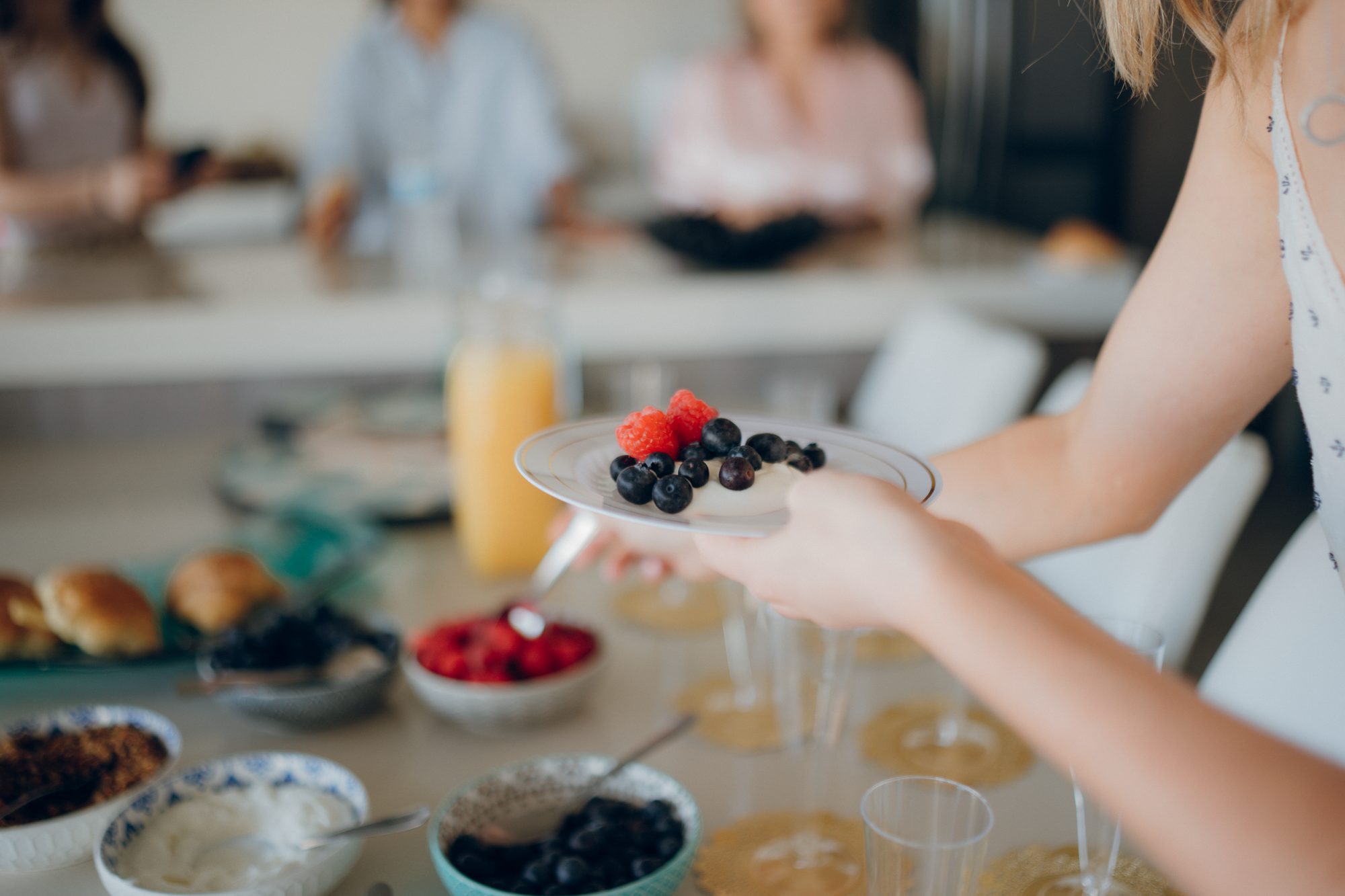 A close-up of a vibrant brunch scene featuring fresh berries, juice, and a diverse group of people.