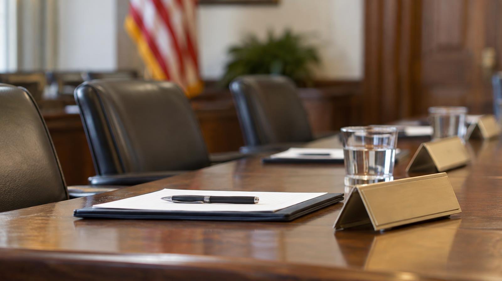 Empty wooden conference table with chairs in a formal meeting room.