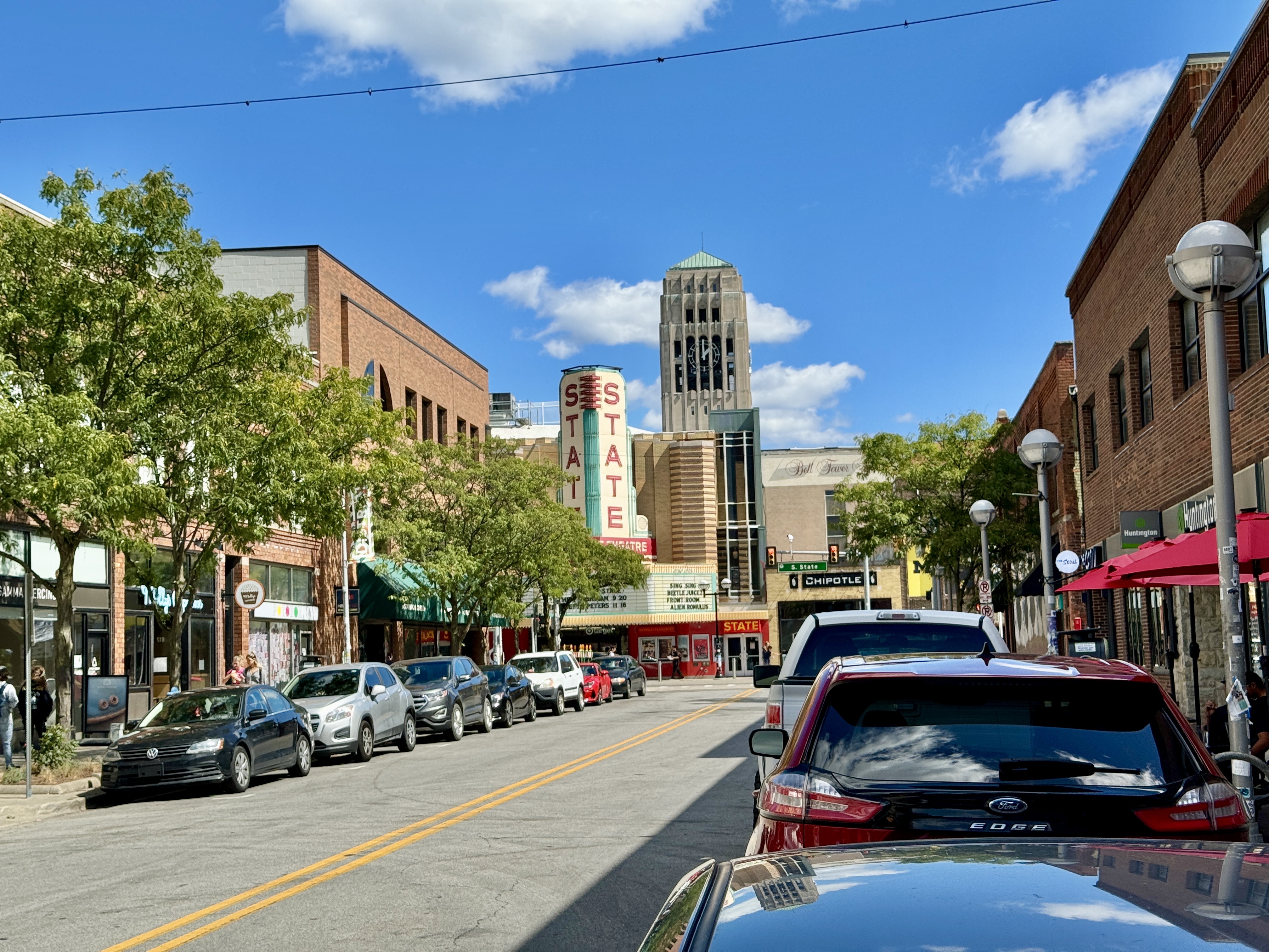 Downtown street lined with brick buildings and a theater marquee under a blue sky.