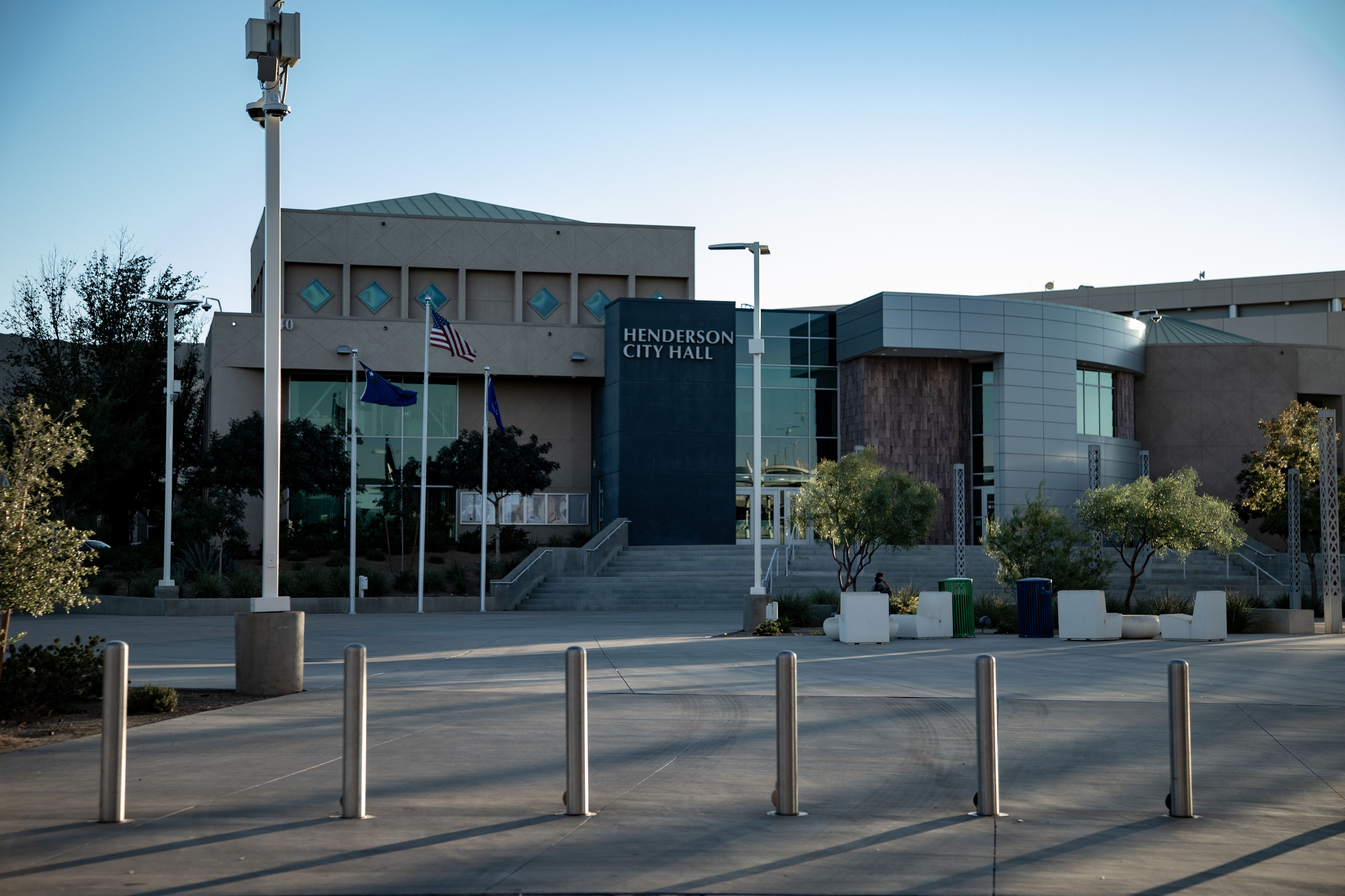 Modern city hall building with flagpoles flying US and state flags out front.