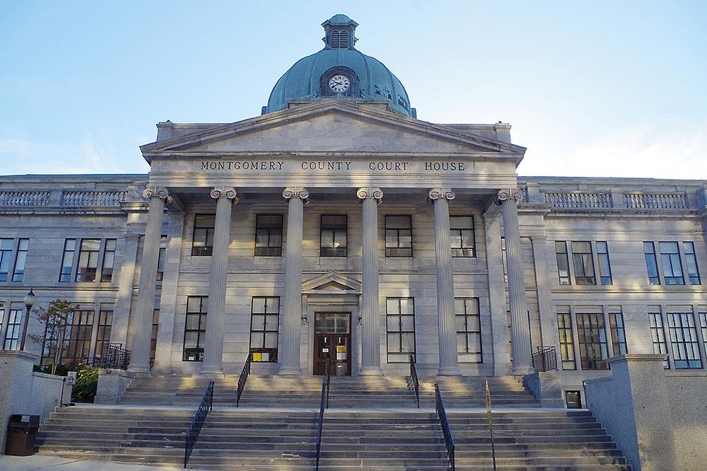 Neoclassical stone courthouse with columns, green dome, and wide front steps.
