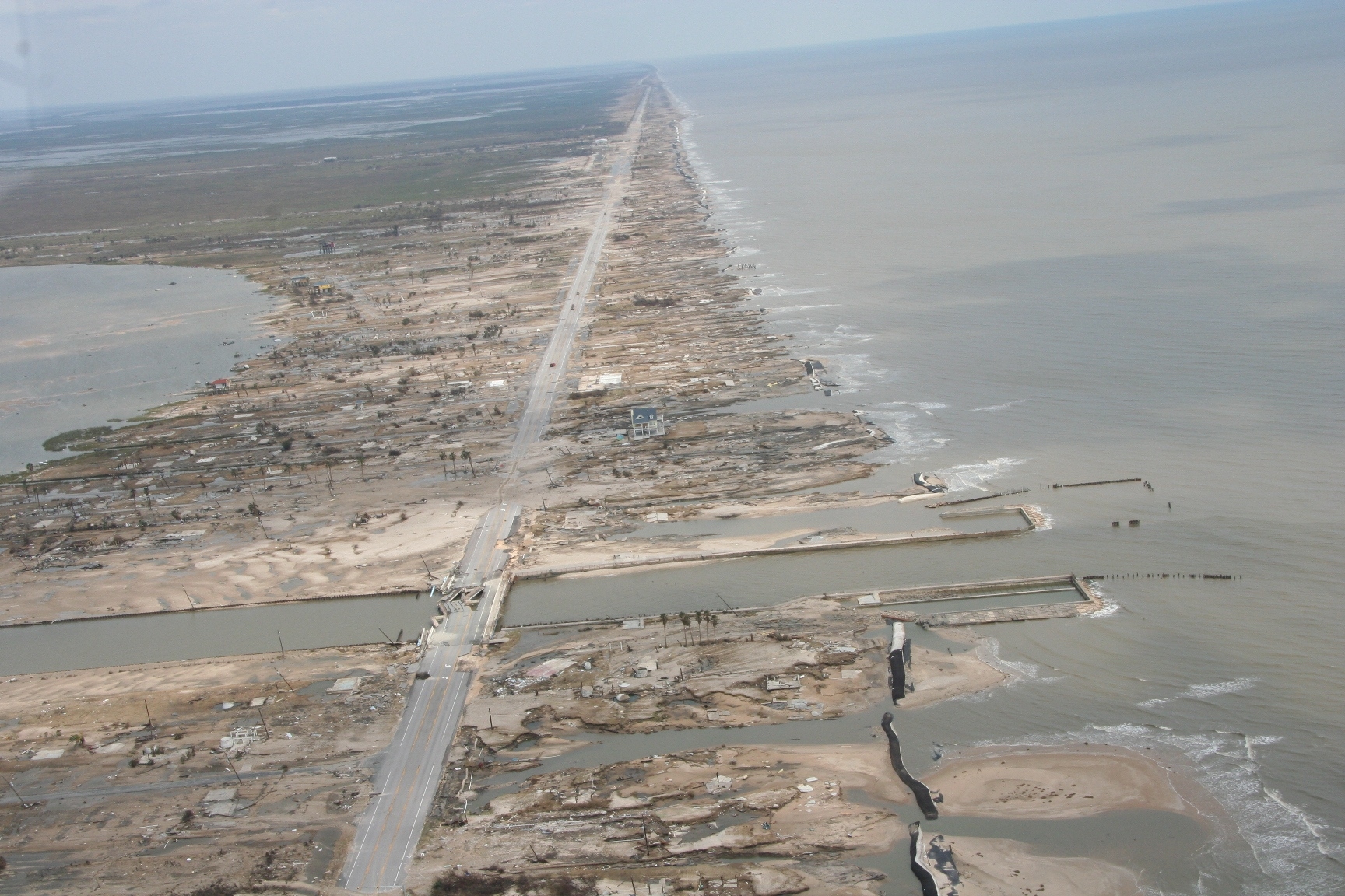 Aerial view of a coastal peninsula devastated by hurricane storm surge.