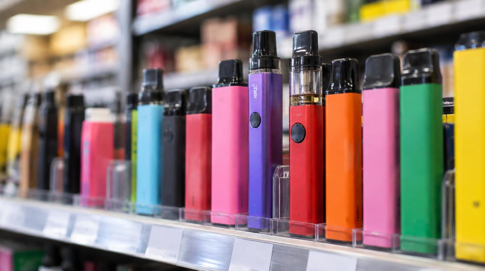 Colorful disposable vape pens lined up on a retail store shelf.