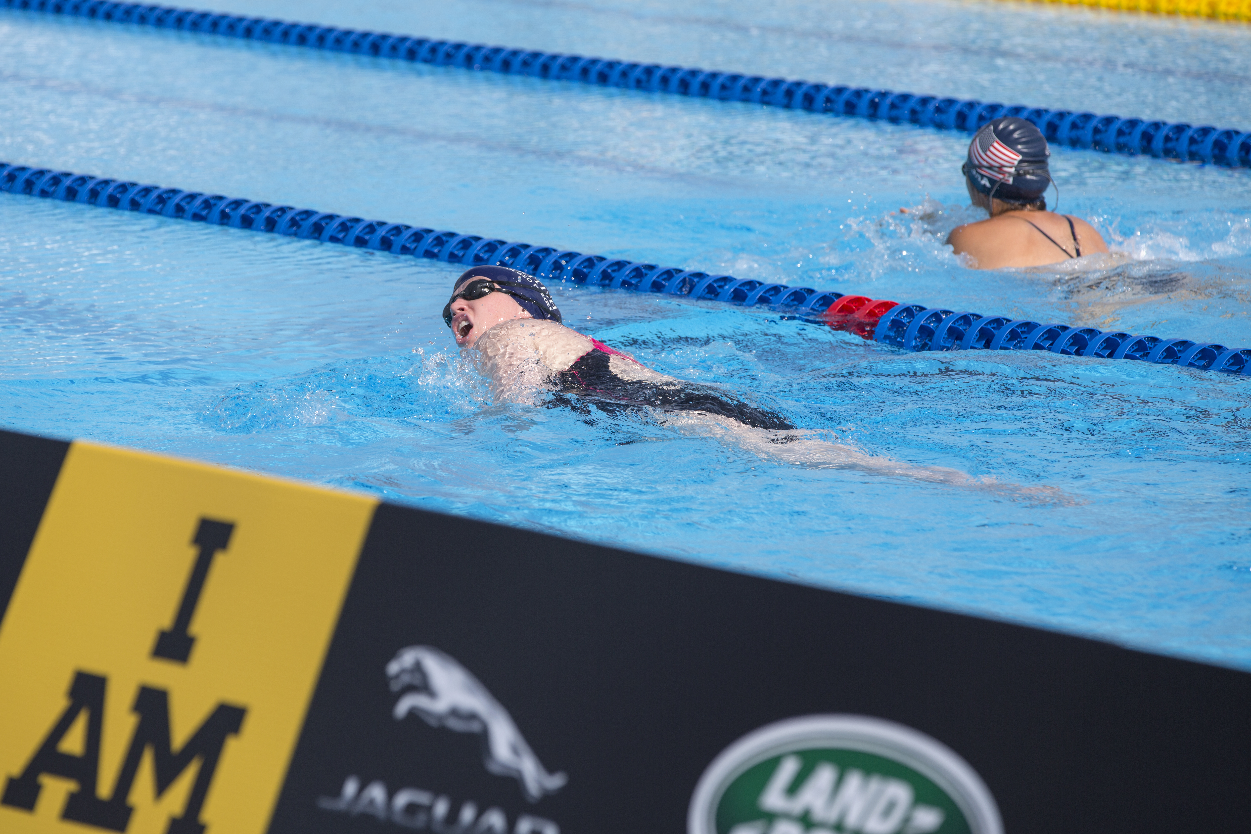 Two swimmers compete side by side in a pool during a breaststroke race.