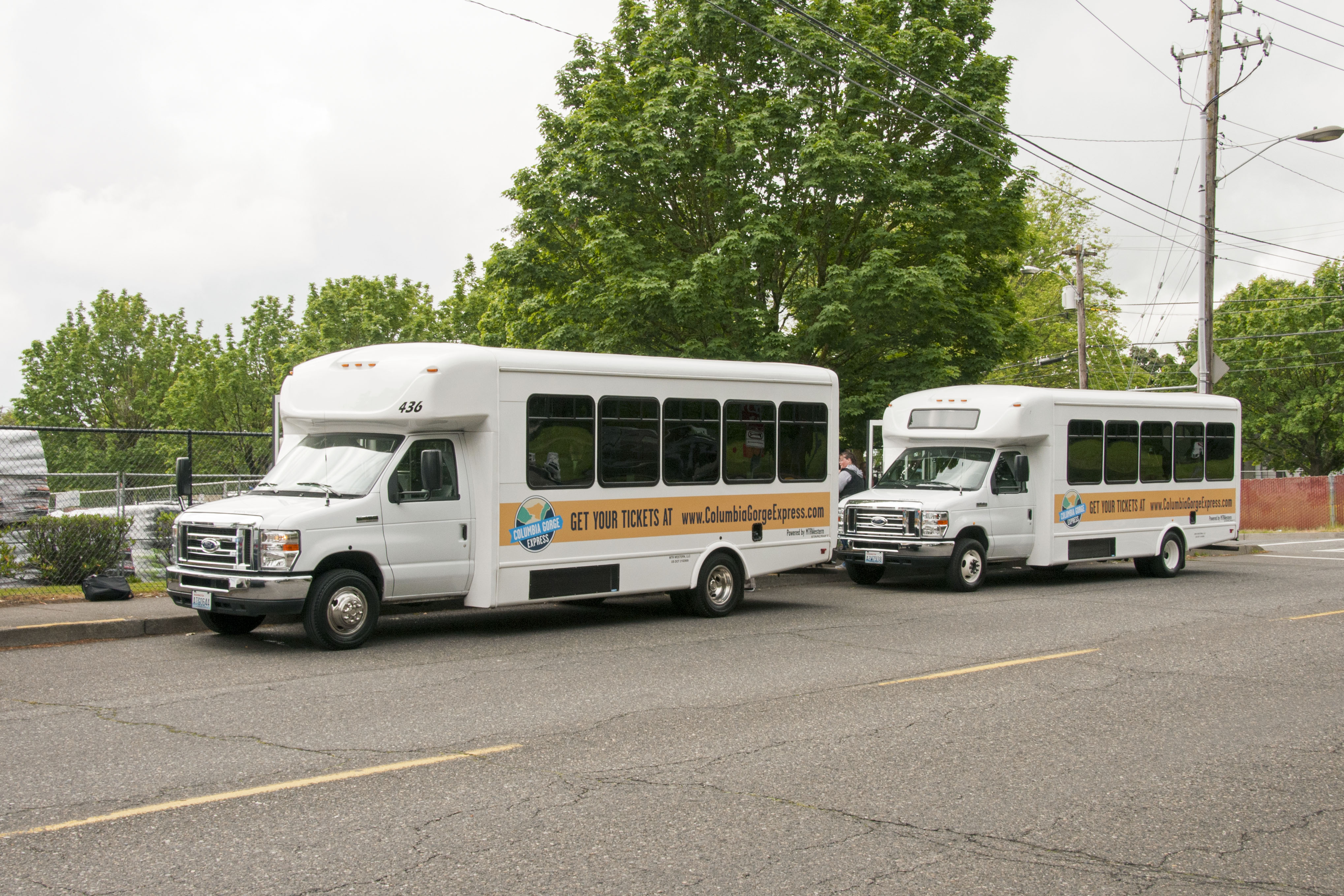 Two white shuttle buses parked side by side at a transit center lot.