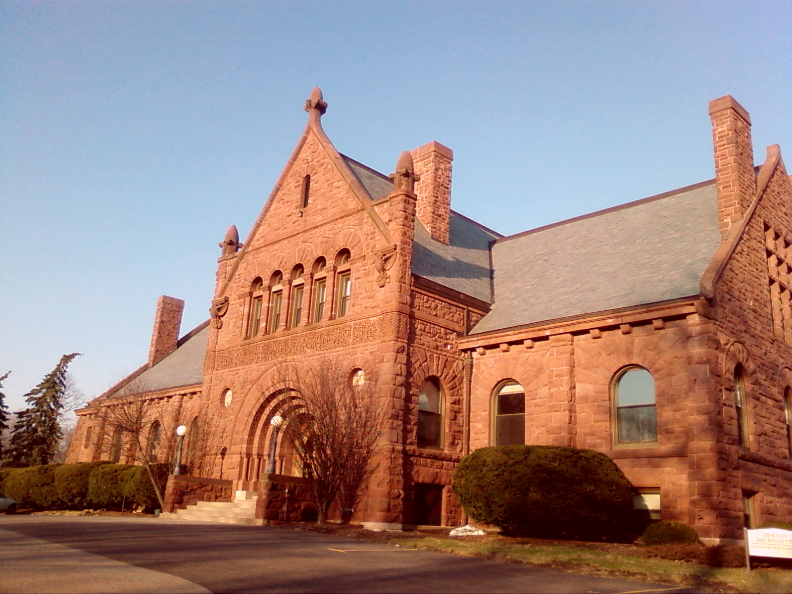 A red sandstone Romanesque Revival building with arched windows on a college campus.