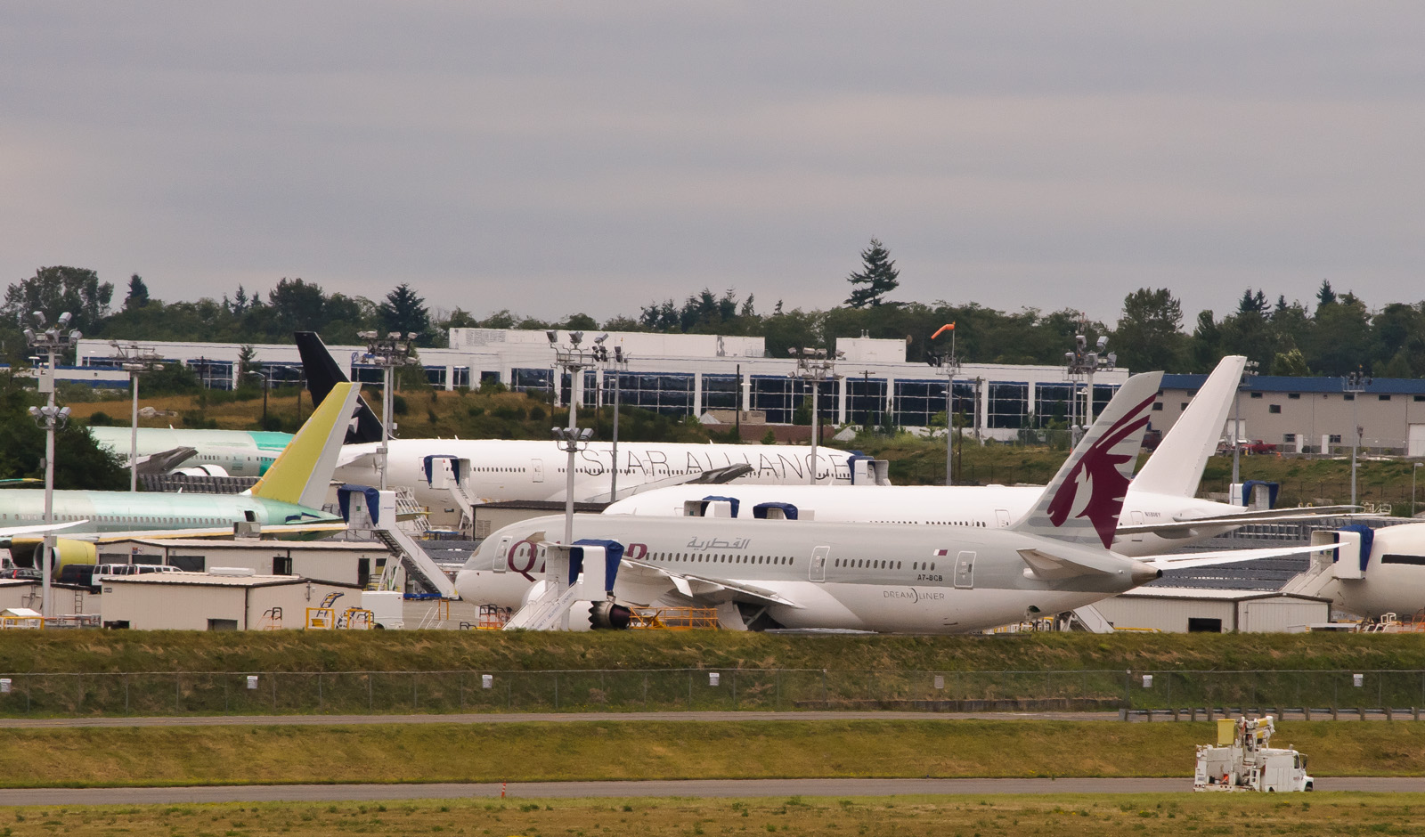 Boeing widebody jets parked on the tarmac outside a large assembly plant.