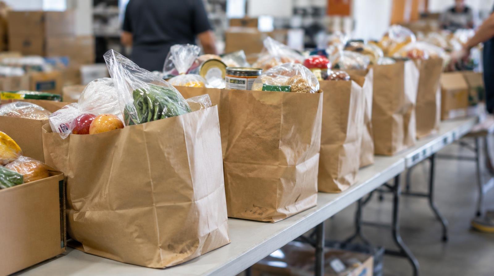 Rows of sealed food bags arranged on a long folding table under bright warehouse lighting.