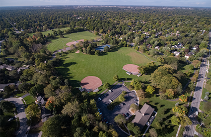 Aerial view of a park with baseball fields, buildings, and several parking lots.