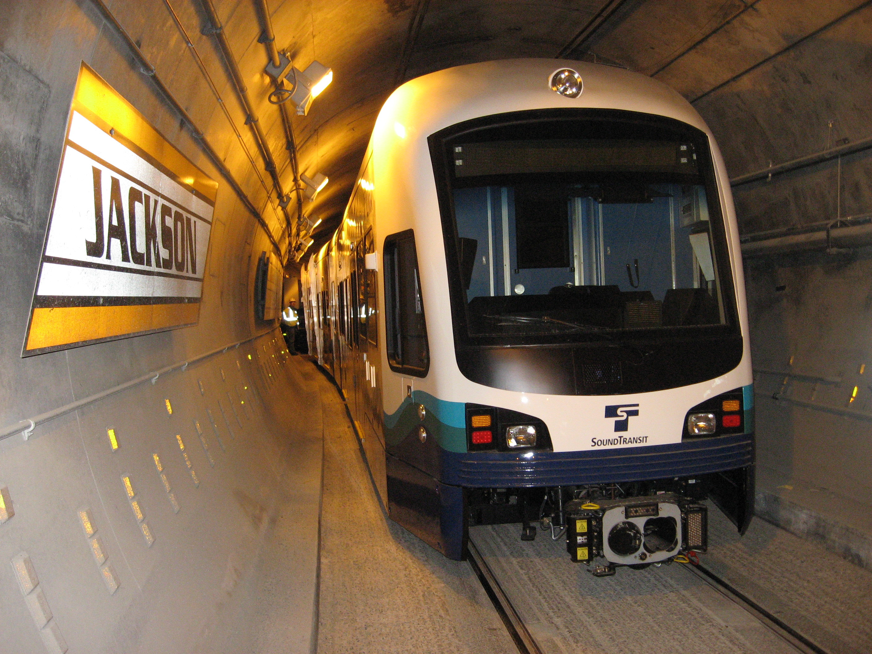 A light rail train moves through a dimly lit underground transit tunnel.