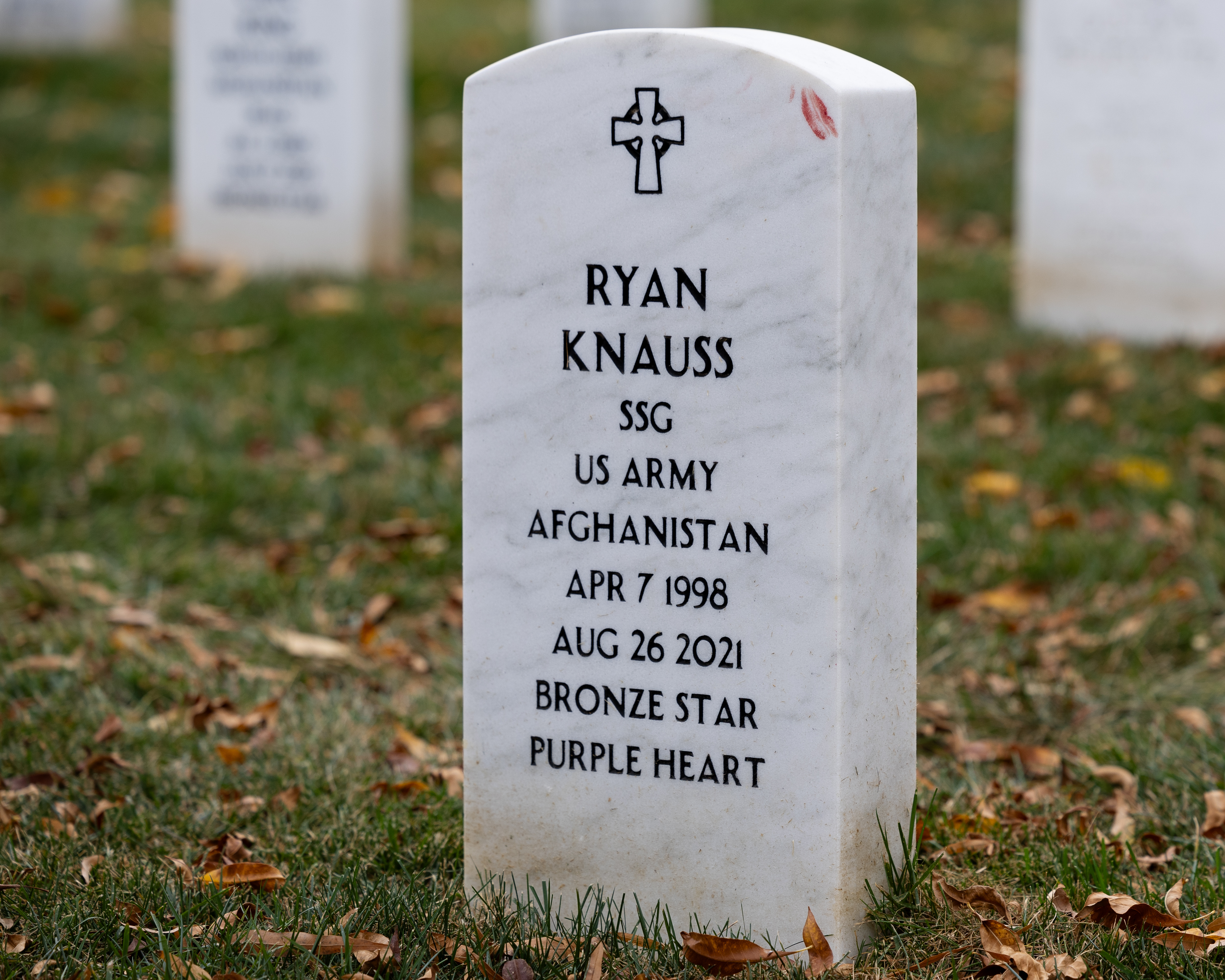 White marble military headstone engraved with Purple Heart at a national cemetery.