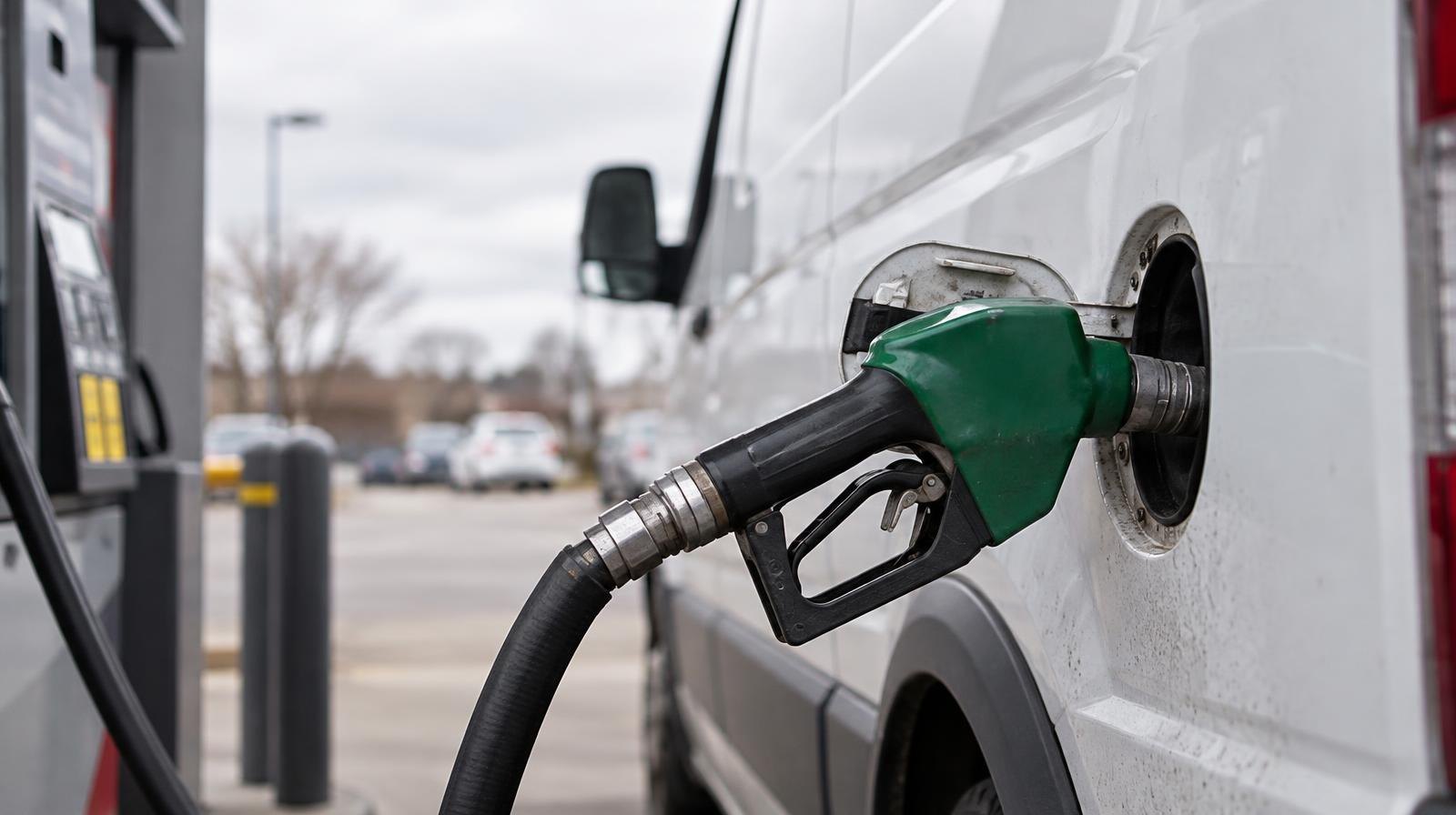 Diesel fuel pump nozzle inserted into a white commercial delivery van.