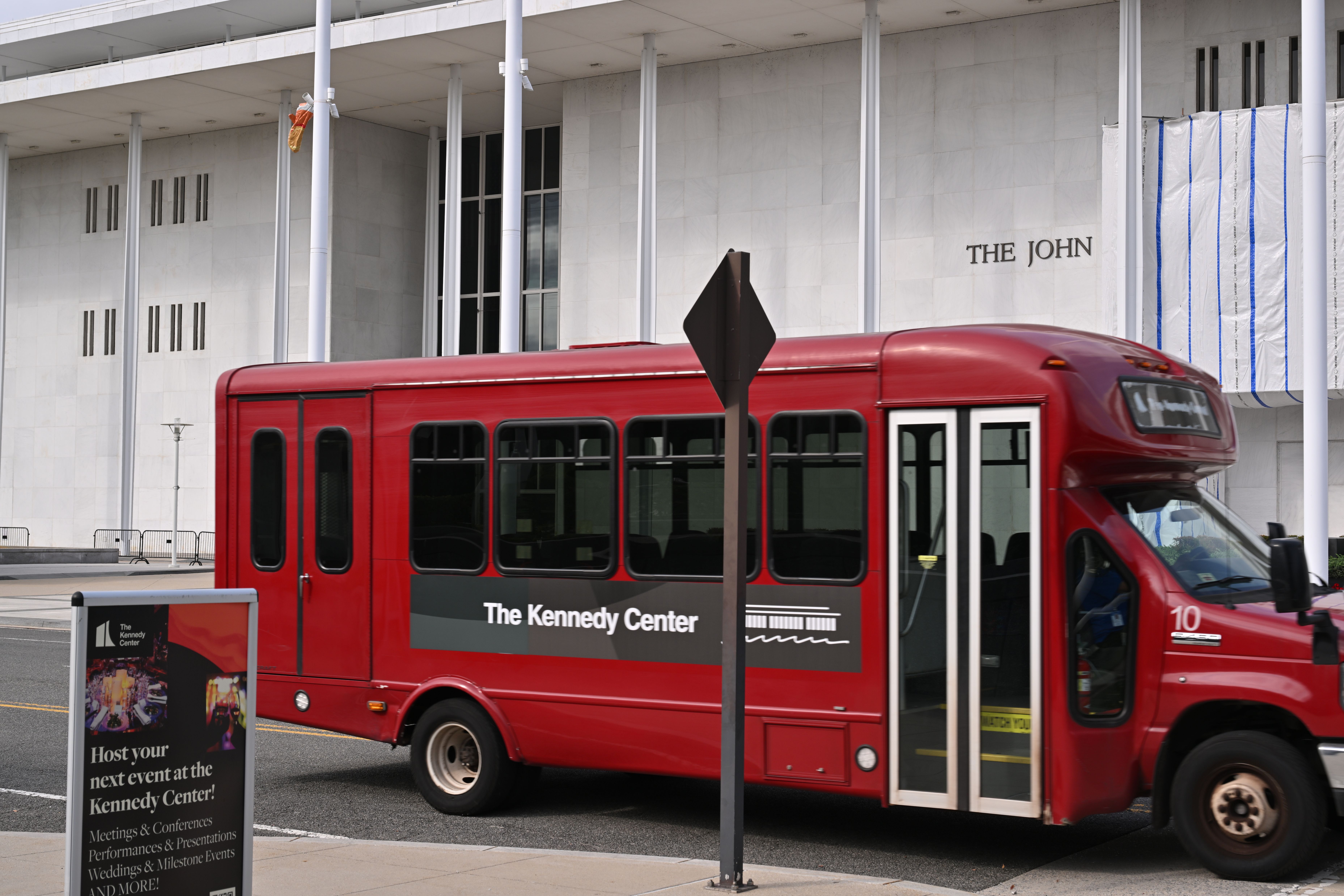 Red Kennedy Center shuttle bus parked in front of the closed performing arts building.