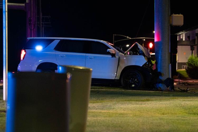 White SUV with blue emergency lights crashed near a utility pole at night.