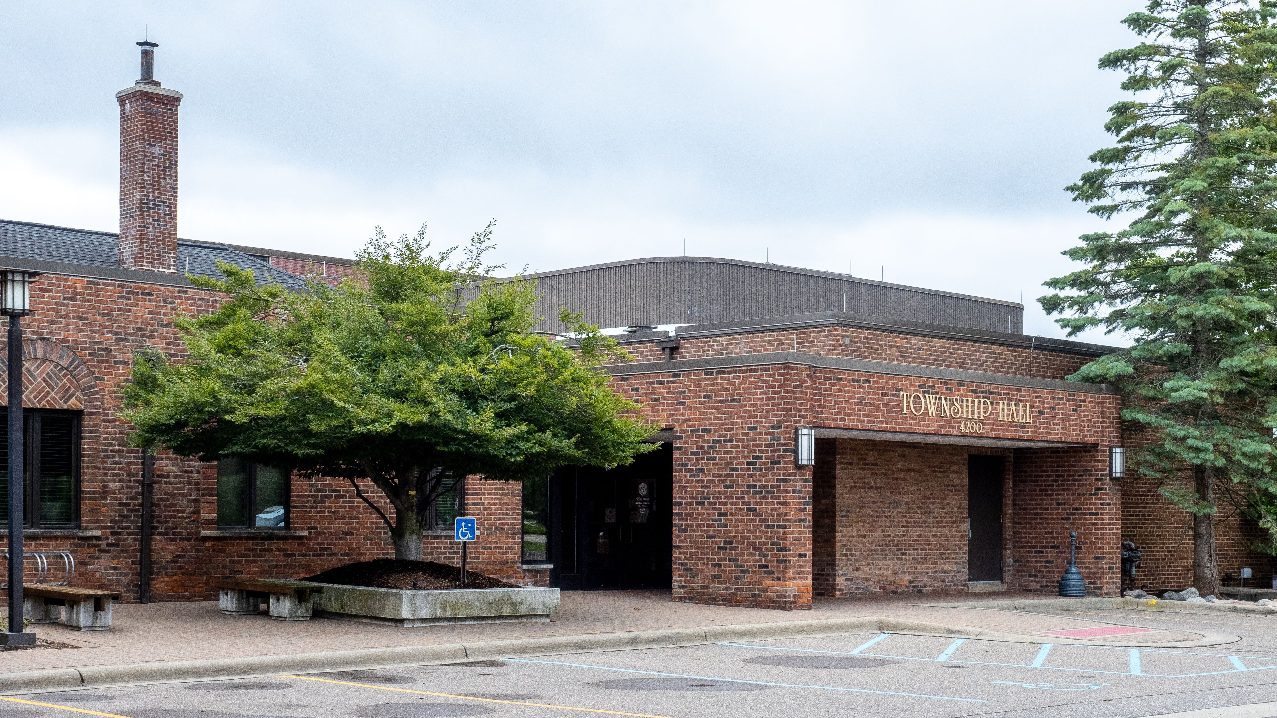 Single-story brick township hall building with covered entrance and trees.