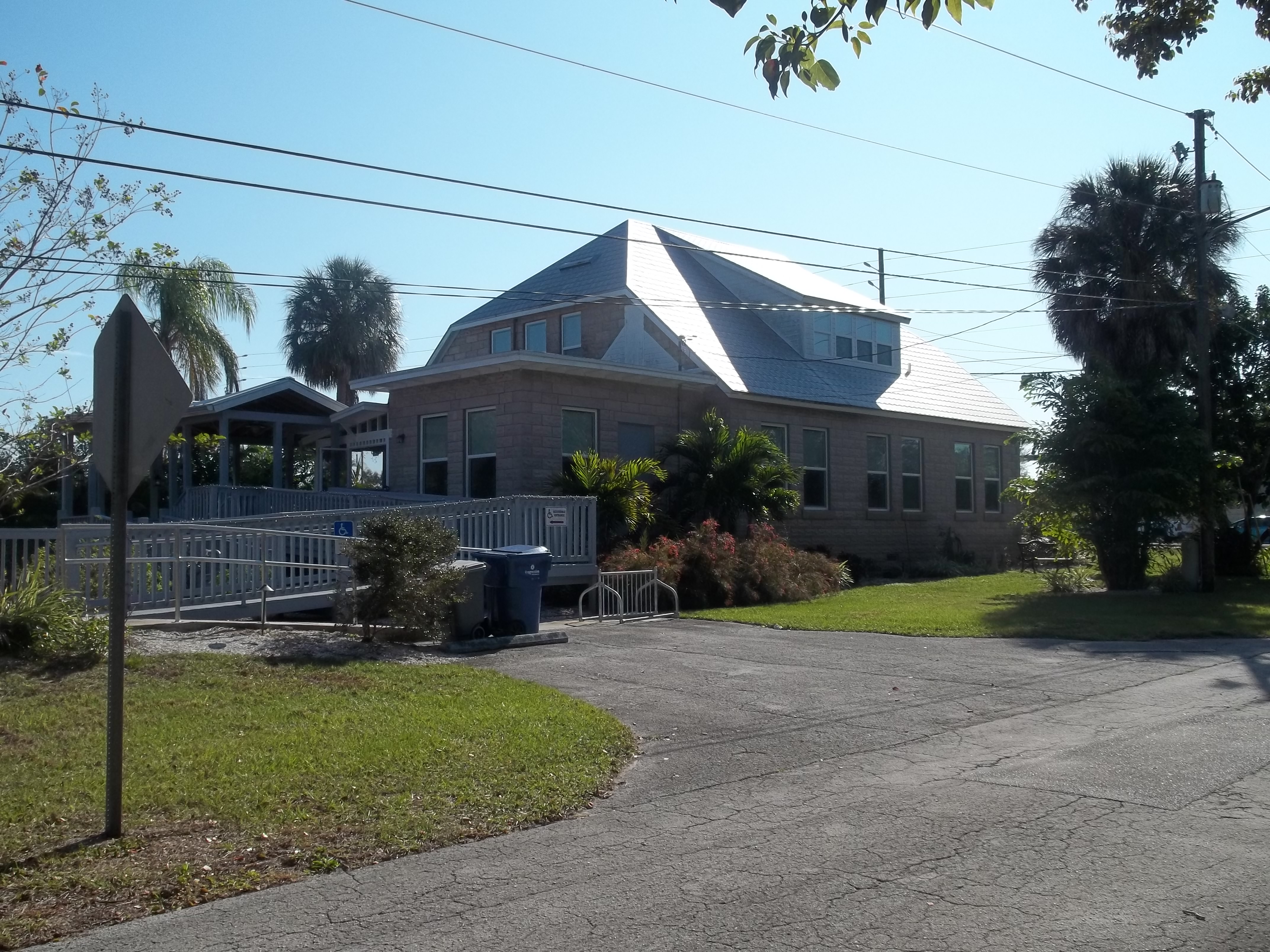 Brick building with a hip roof and palm trees in a Florida community.