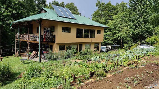 A two-story house with solar panels on a green metal roof.