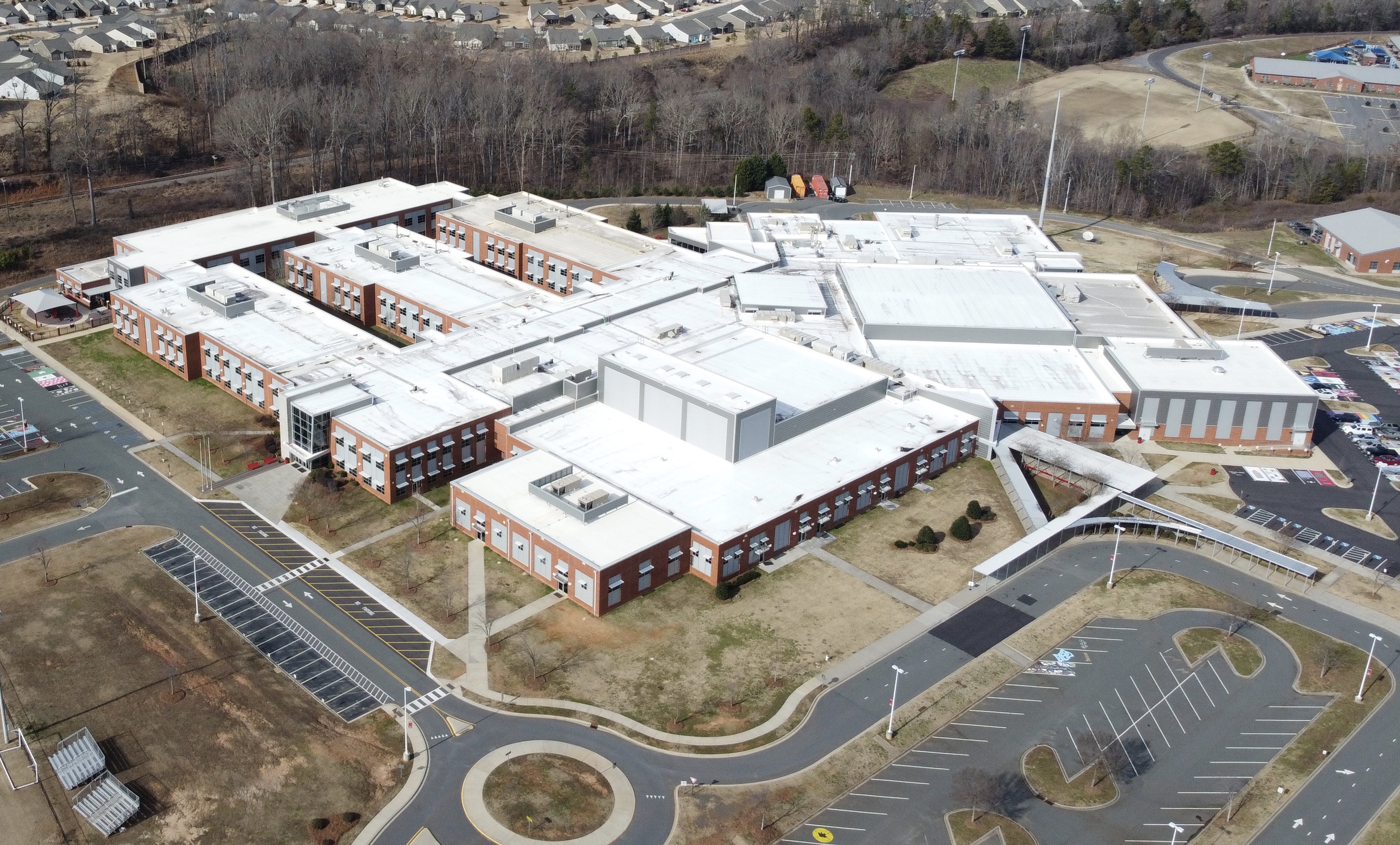 Aerial view of a large multi-wing brick high school campus with parking lots.