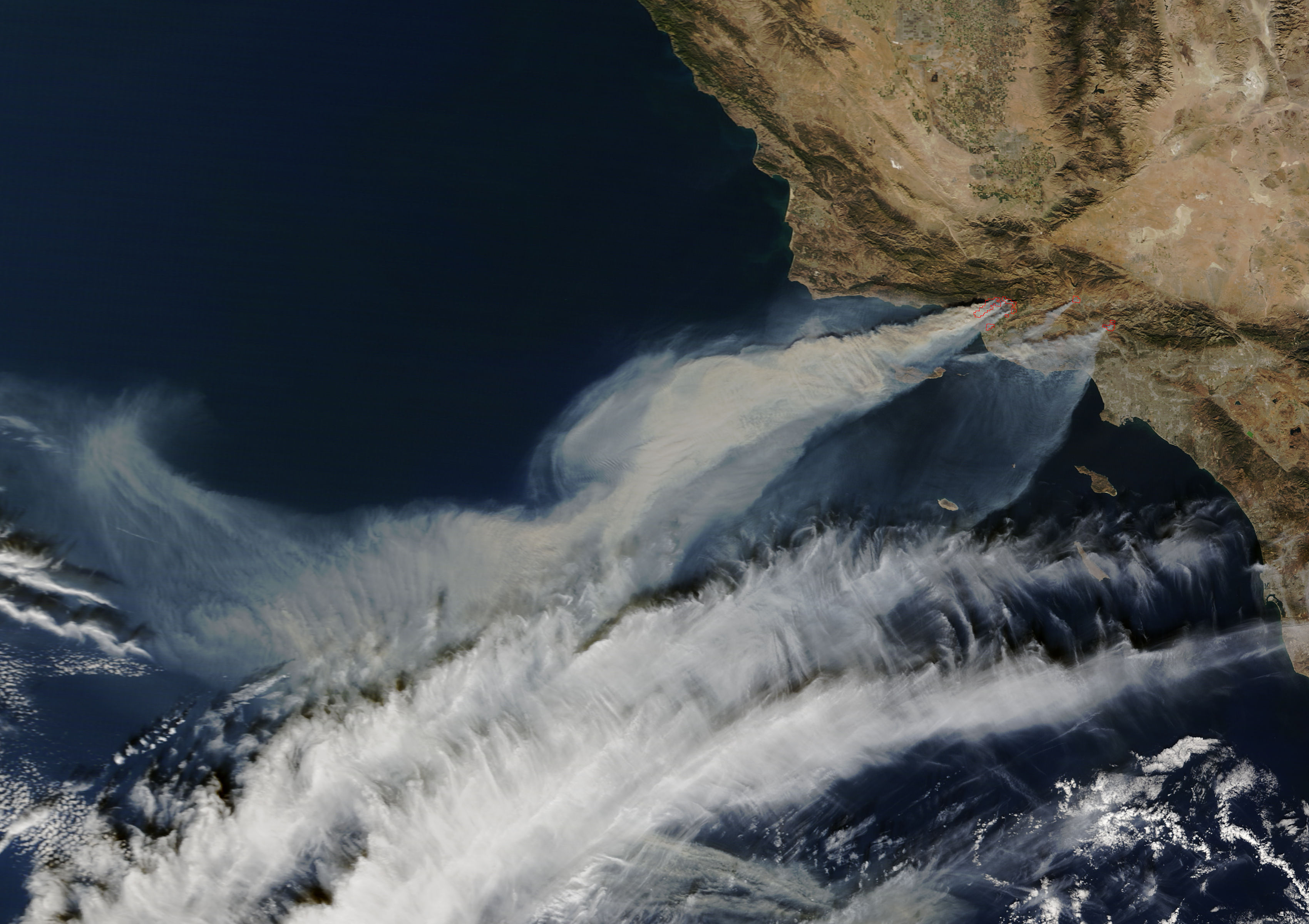 Satellite view of thick smoke plumes from Southern California wildfires streaming over the Pacific Ocean.