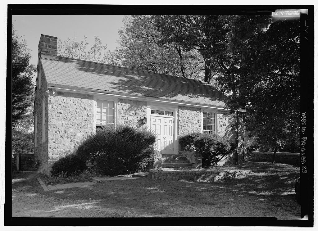 Exterior of a small single-story stone library building with a central entrance door.