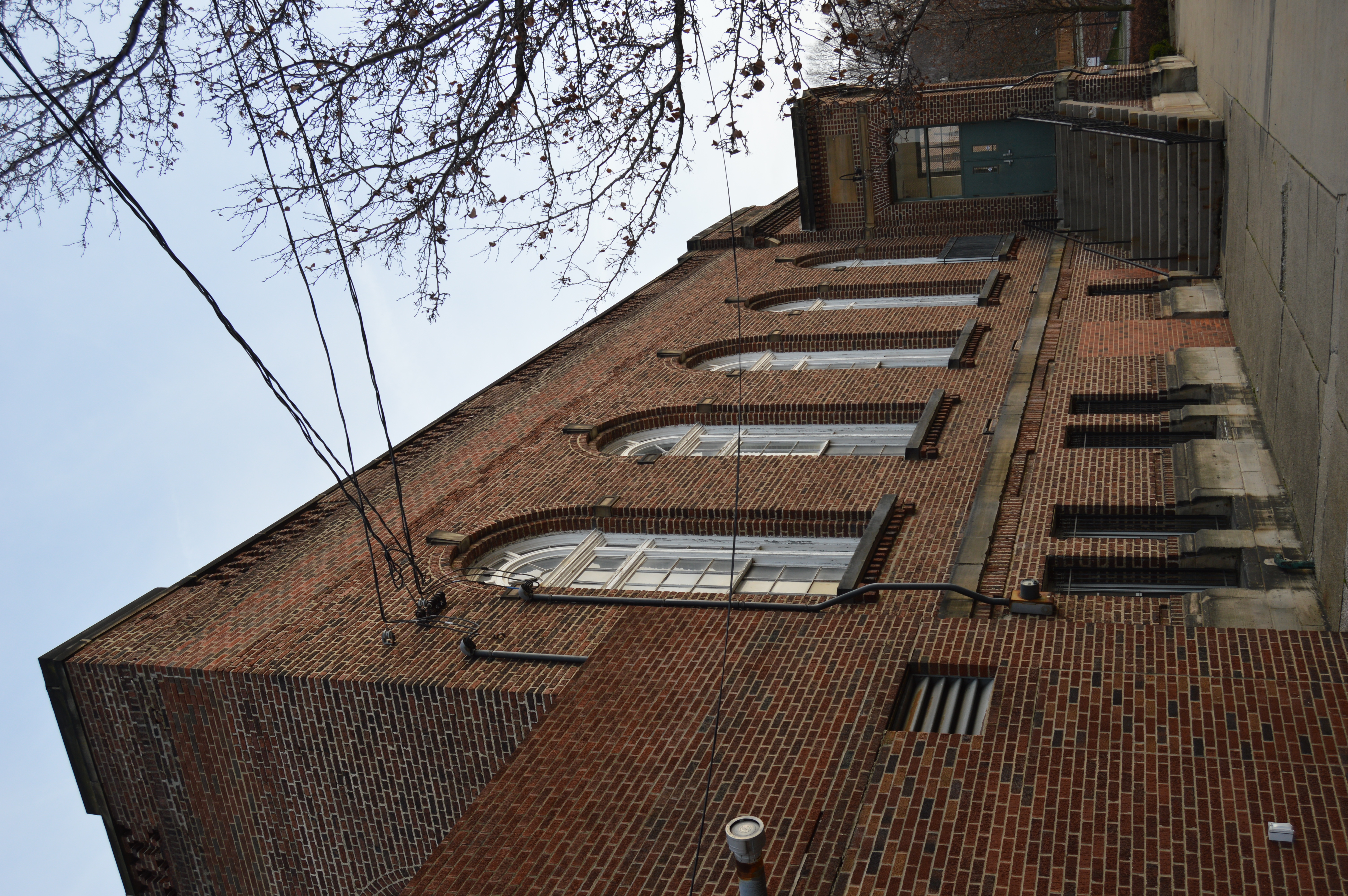 Red brick public library building exterior with arched windows and stone entrance steps.