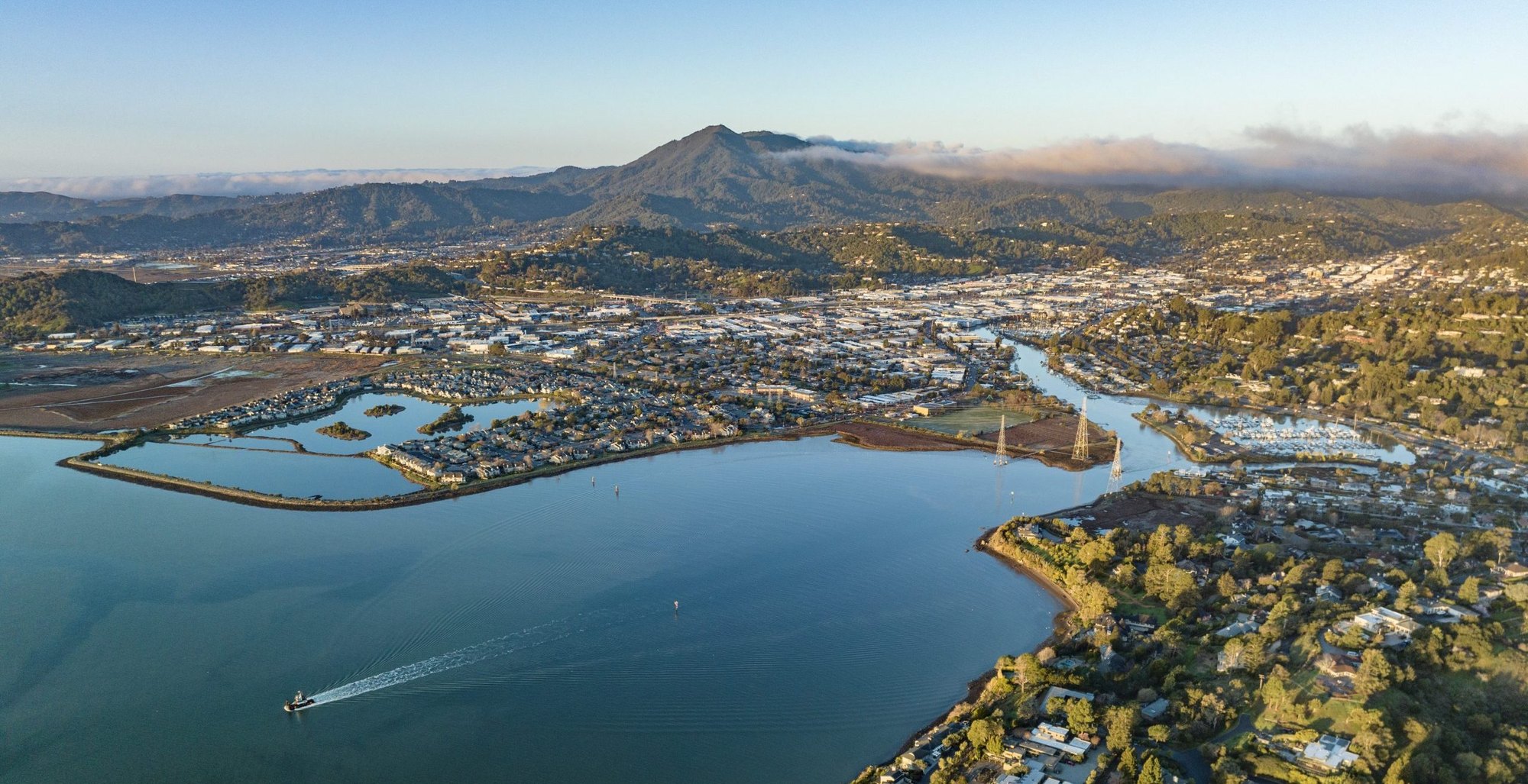 Aerial view of a coastal city with bay shoreline, tidal waterways, and low-lying neighborhoods.