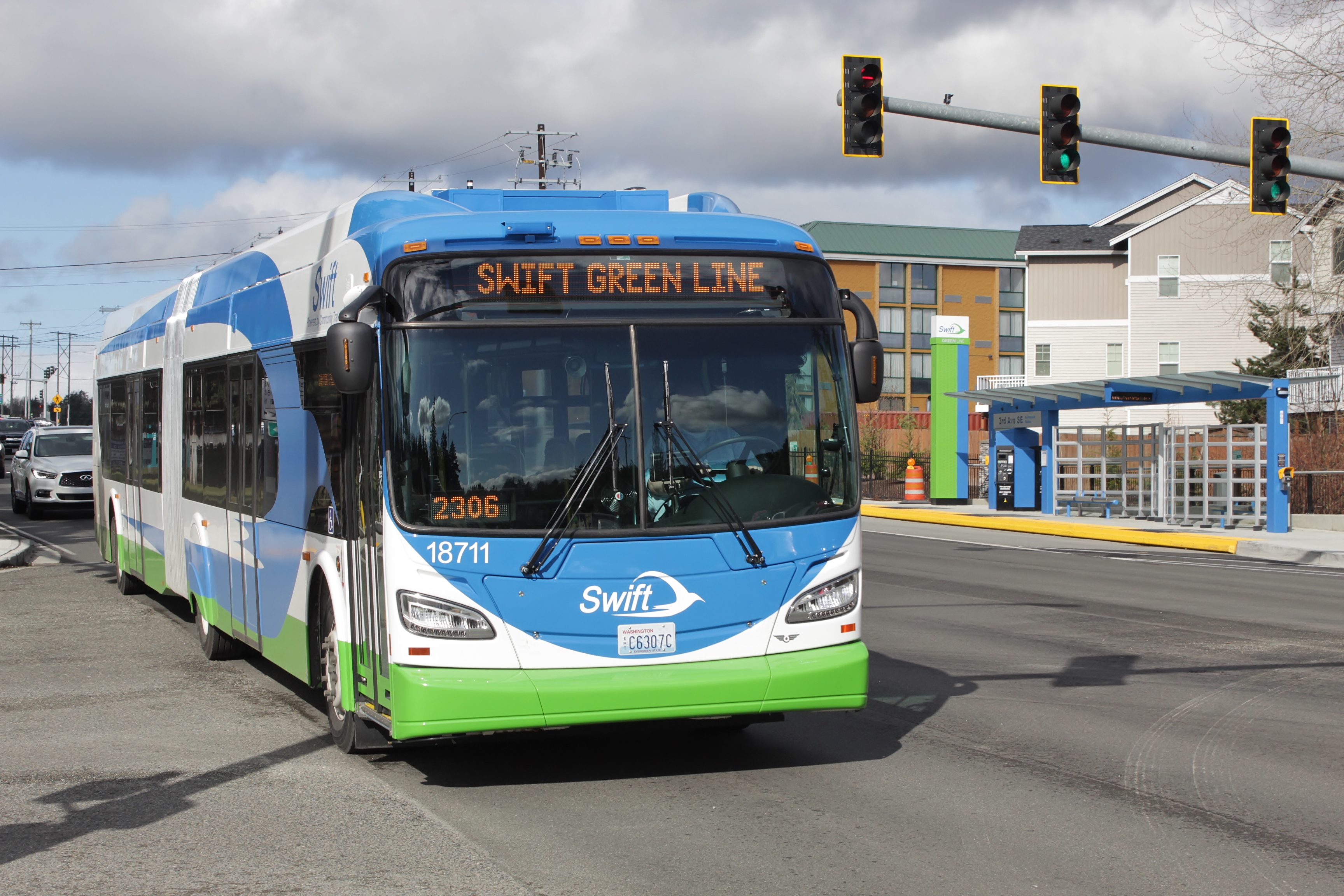 An articulated public transit bus at a bus rapid transit station on a sunny day.
