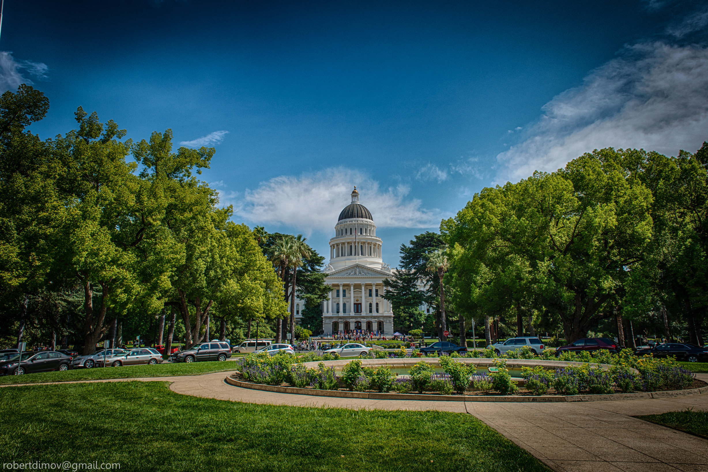 California State Capitol dome and neoclassical facade seen from park grounds with circular garden.
