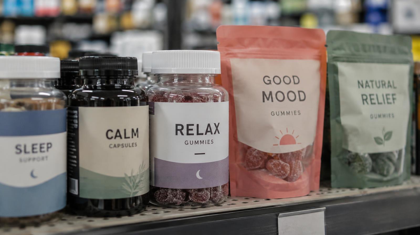 Rows of small supplement bottles and gummy packages on a retail store shelf.