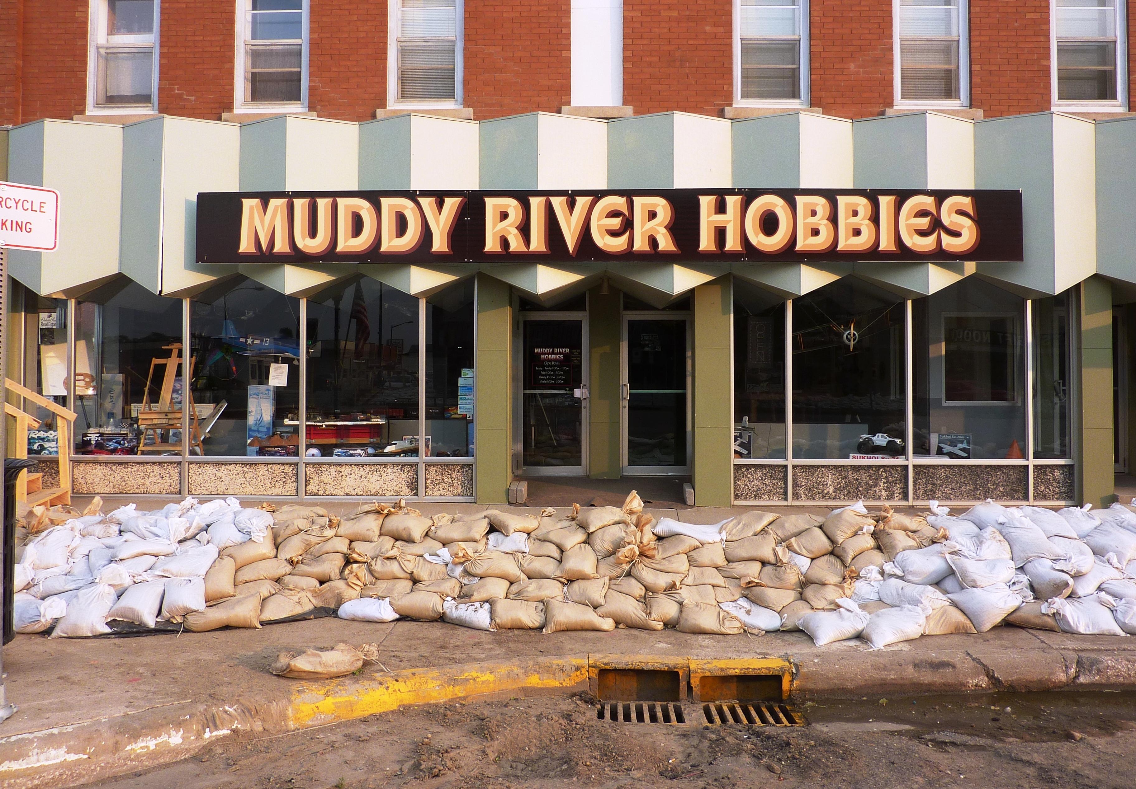 White sandbags stacked in a row along the front of a brick building.