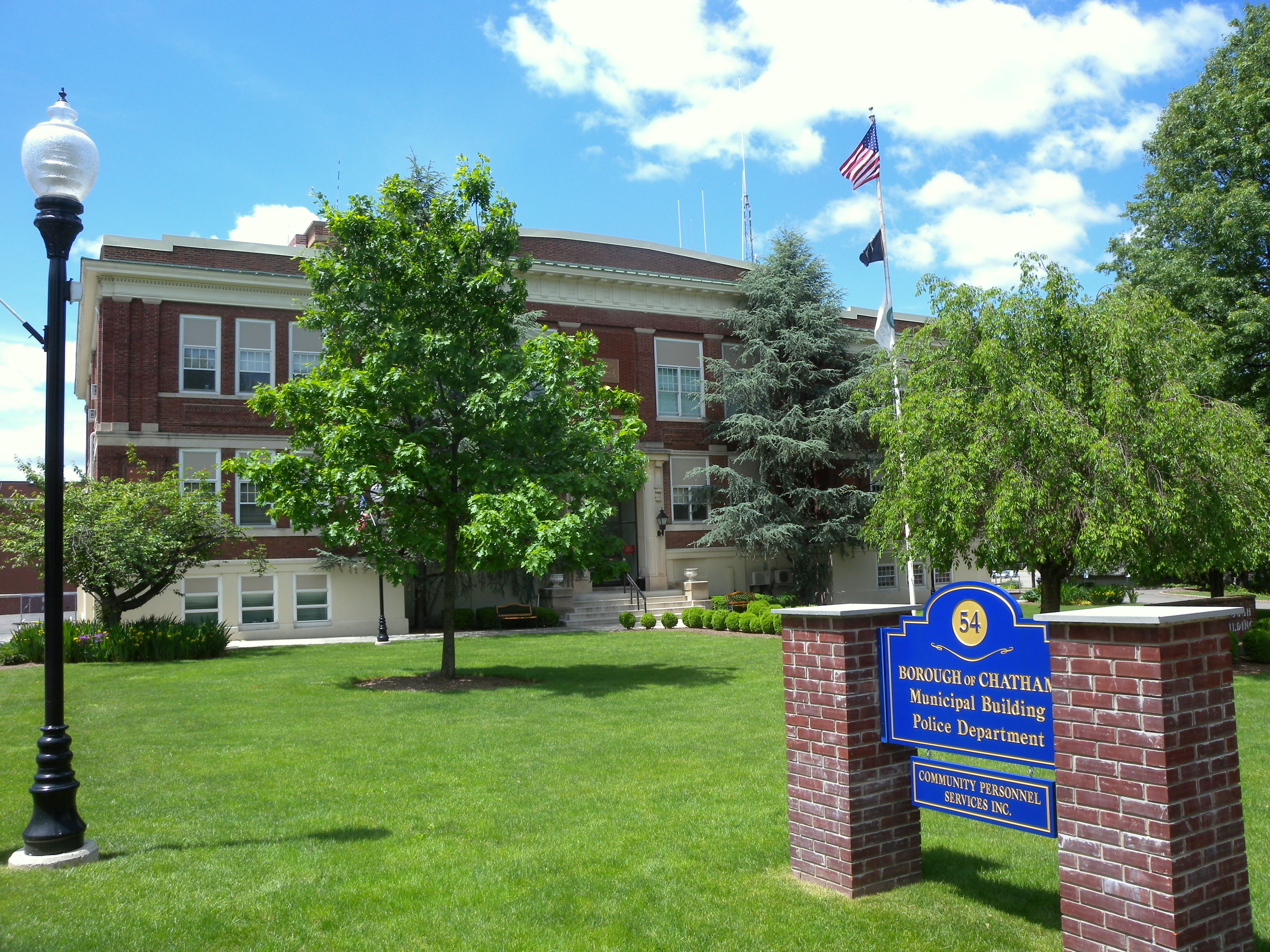 Brick municipal building with American flags and a blue sign reading Borough of Chatham Municipal Building.